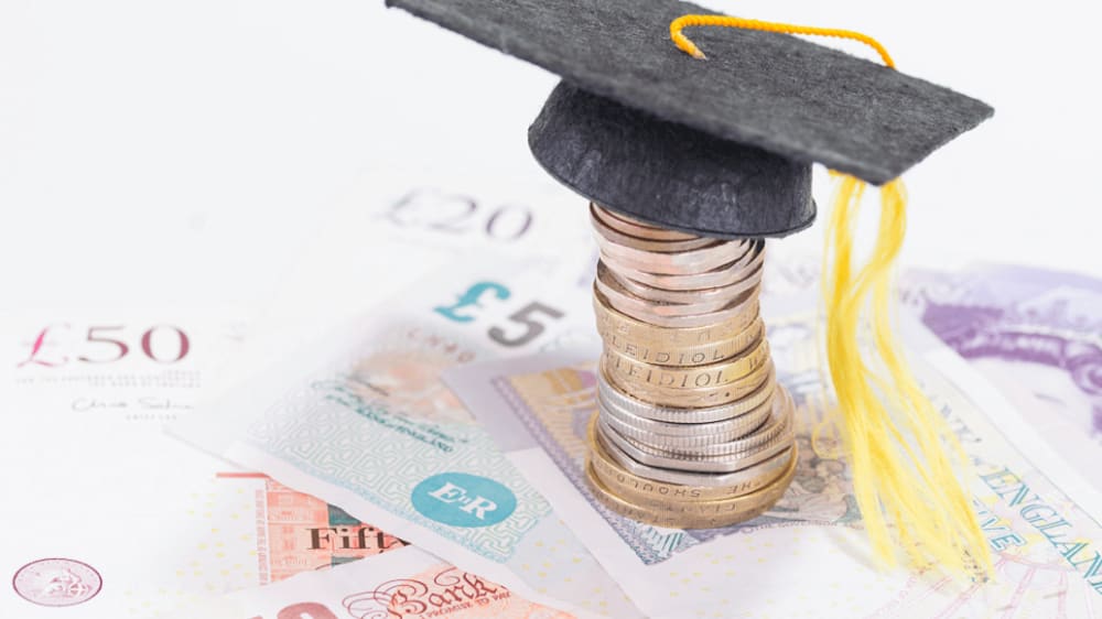 Photograph of a stack of coins with a miniature graduation cap on top