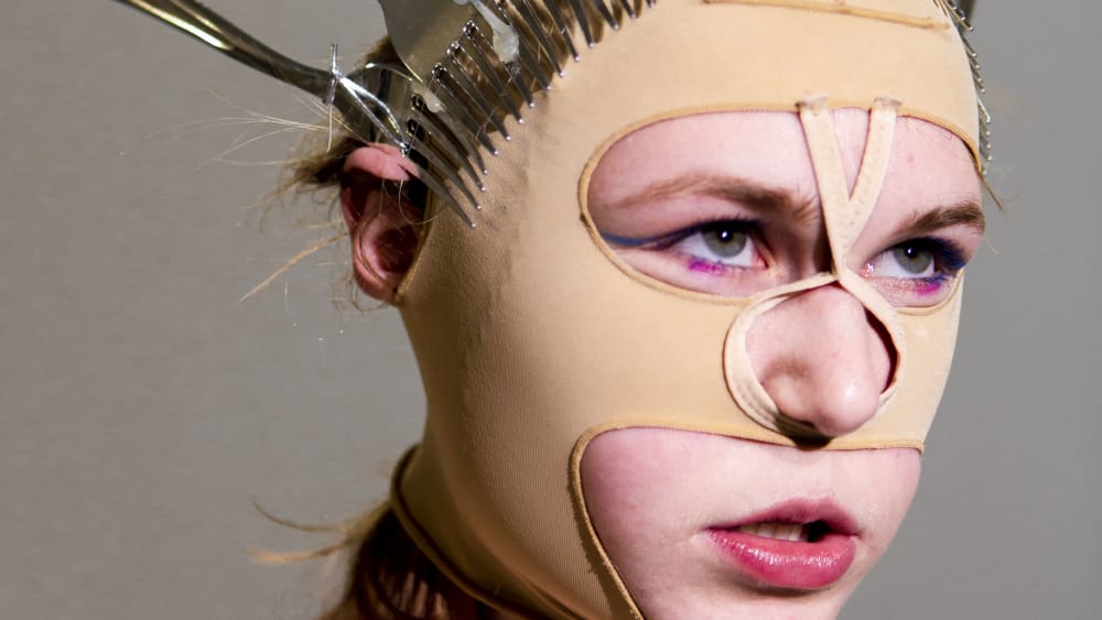 Portrait of a face wearing a mask of metal spoons
