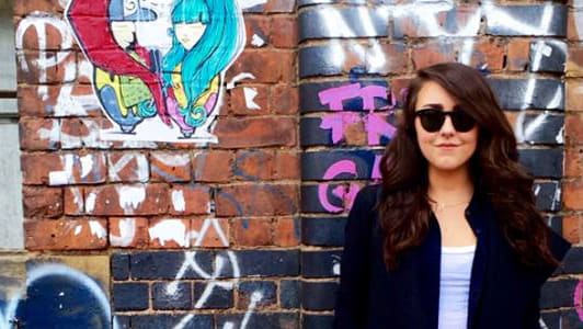Elizabeth Delaney standing in front of a wall with graffiti.