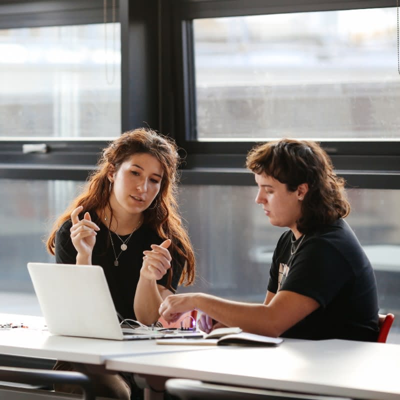 Two people talking in front of a laptop.