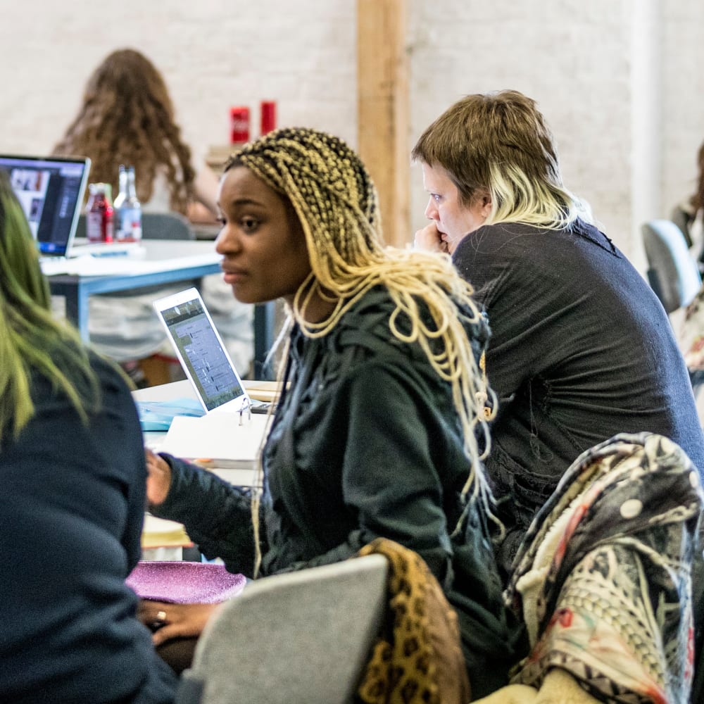 Students working at tables inside Central Saint Martins' Library