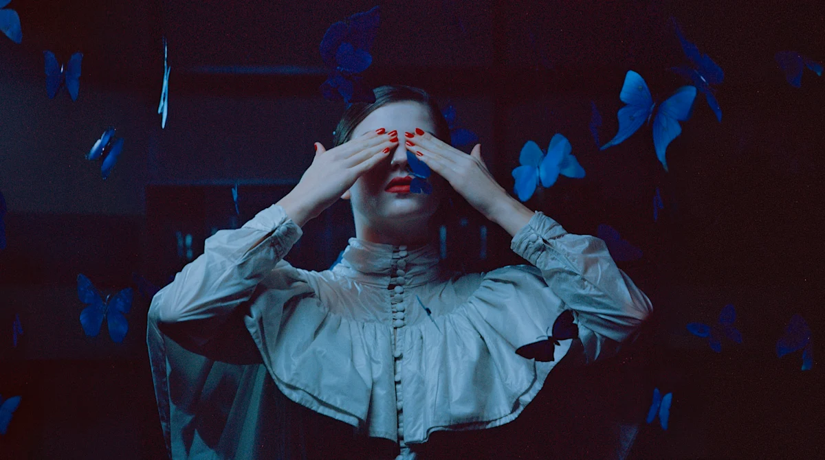Female model with red nails covering her eyes. 