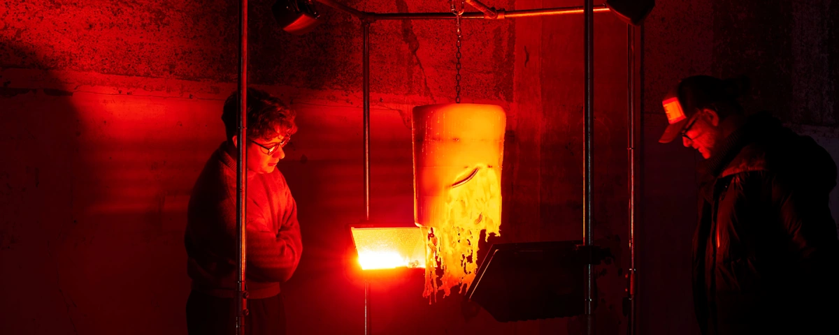 Two people look at a sculpture under a red light.