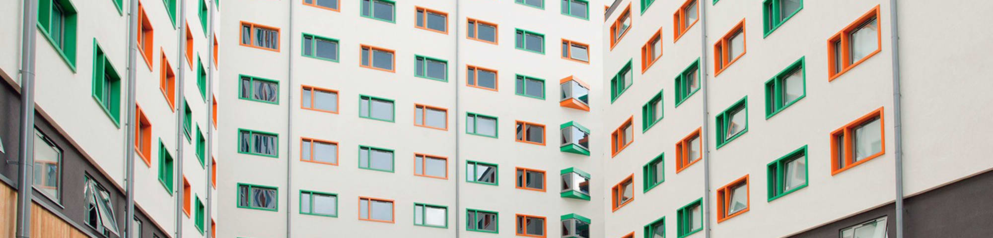 Shot of the building from inside the courtyard, showing the building reach up to 9 floors with orange and green windows.
