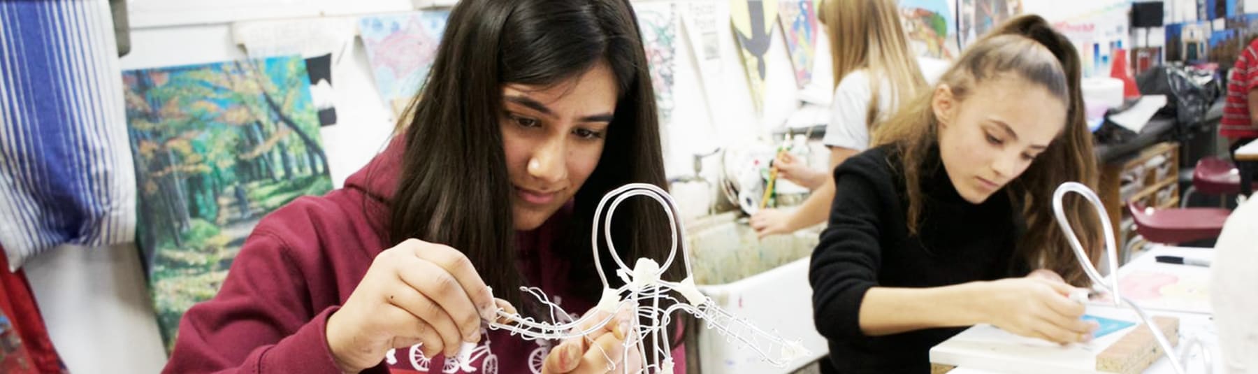 Students working in a classroom making wire figure sculpture.
