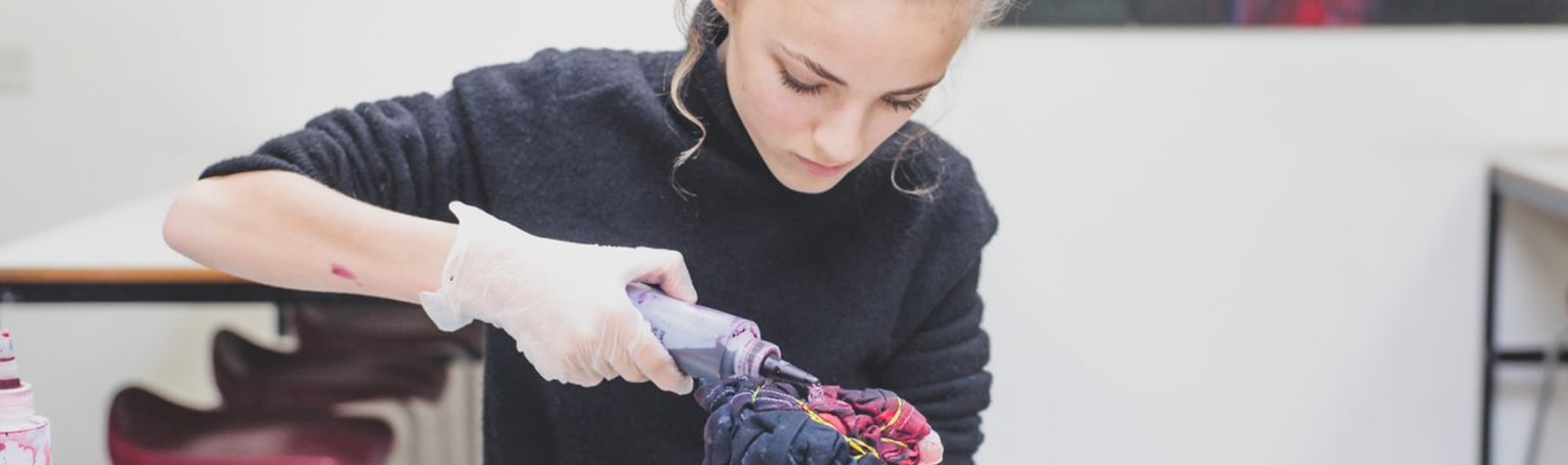 Student tie-dyeing fabric in a classroom.
