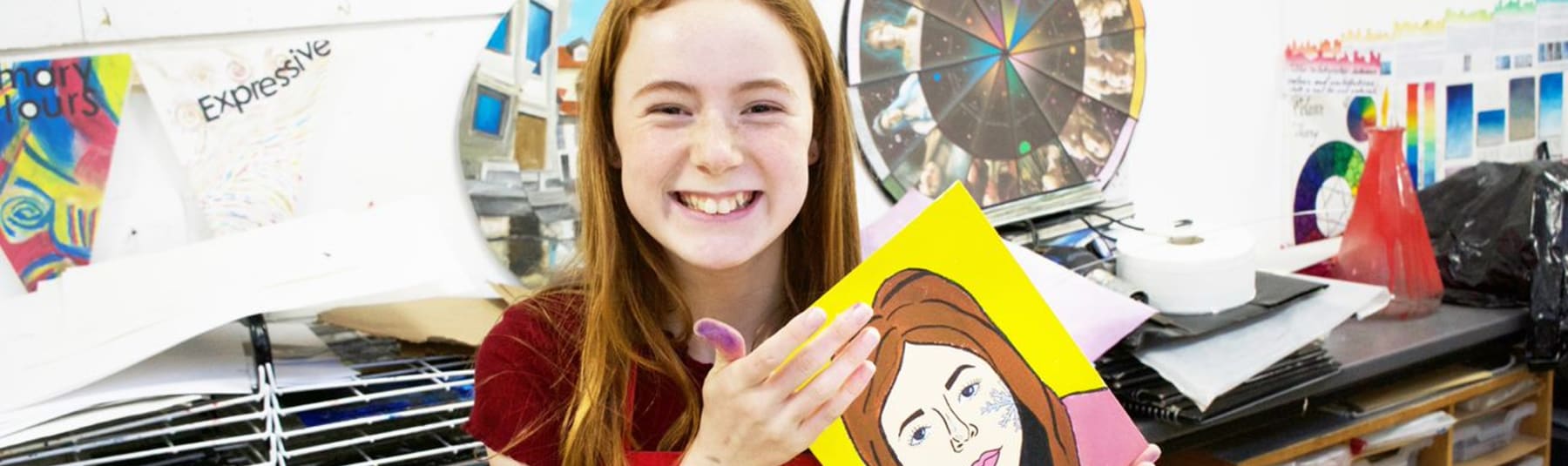 Girl holding up a painted self portrait.