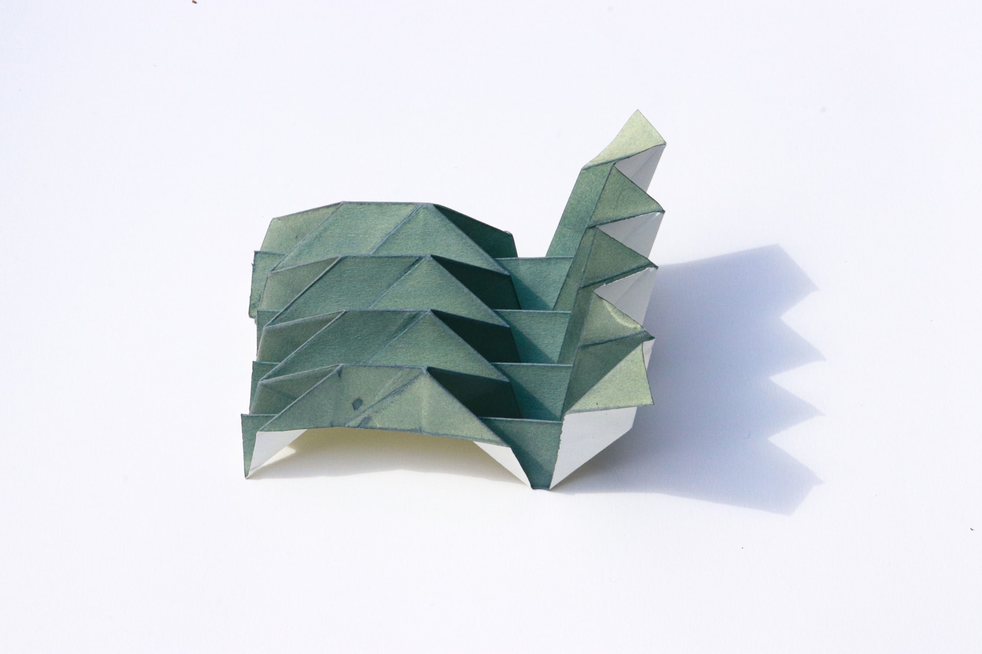 Pleated geometric origami sculpture which angles upwards towards the right.