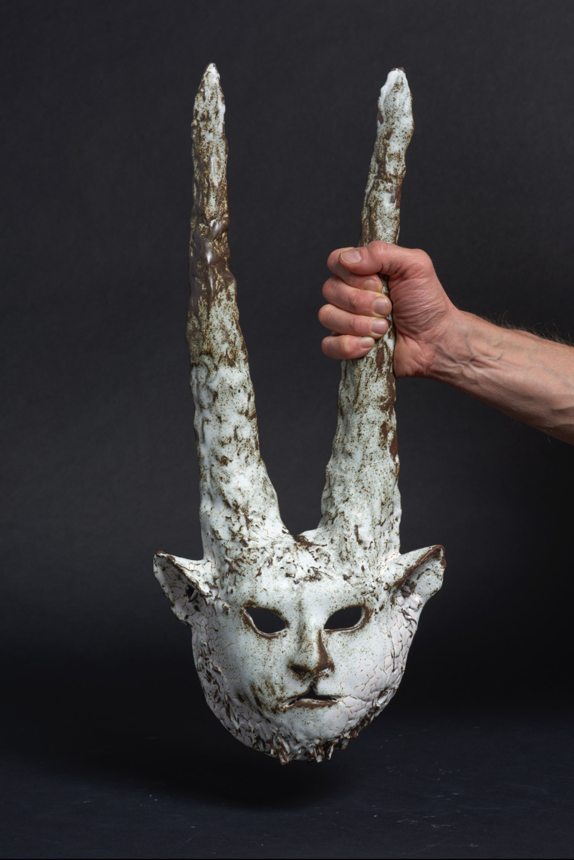 a ceramic mask with goat horns and snow leopard face
