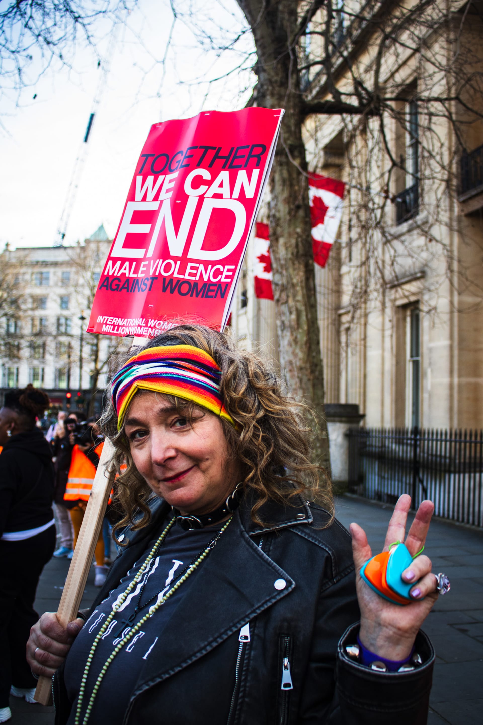Portrait of a woman with a rainbow headband, holding a placard reading: "Together we can end violence against women" 