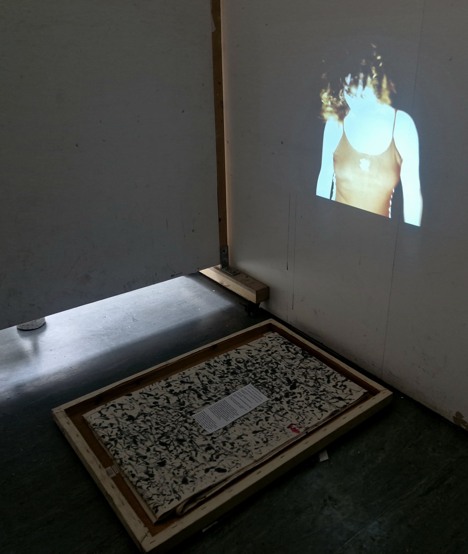 Close Up Projection Of A Womans Chest and A Small Black Painting 