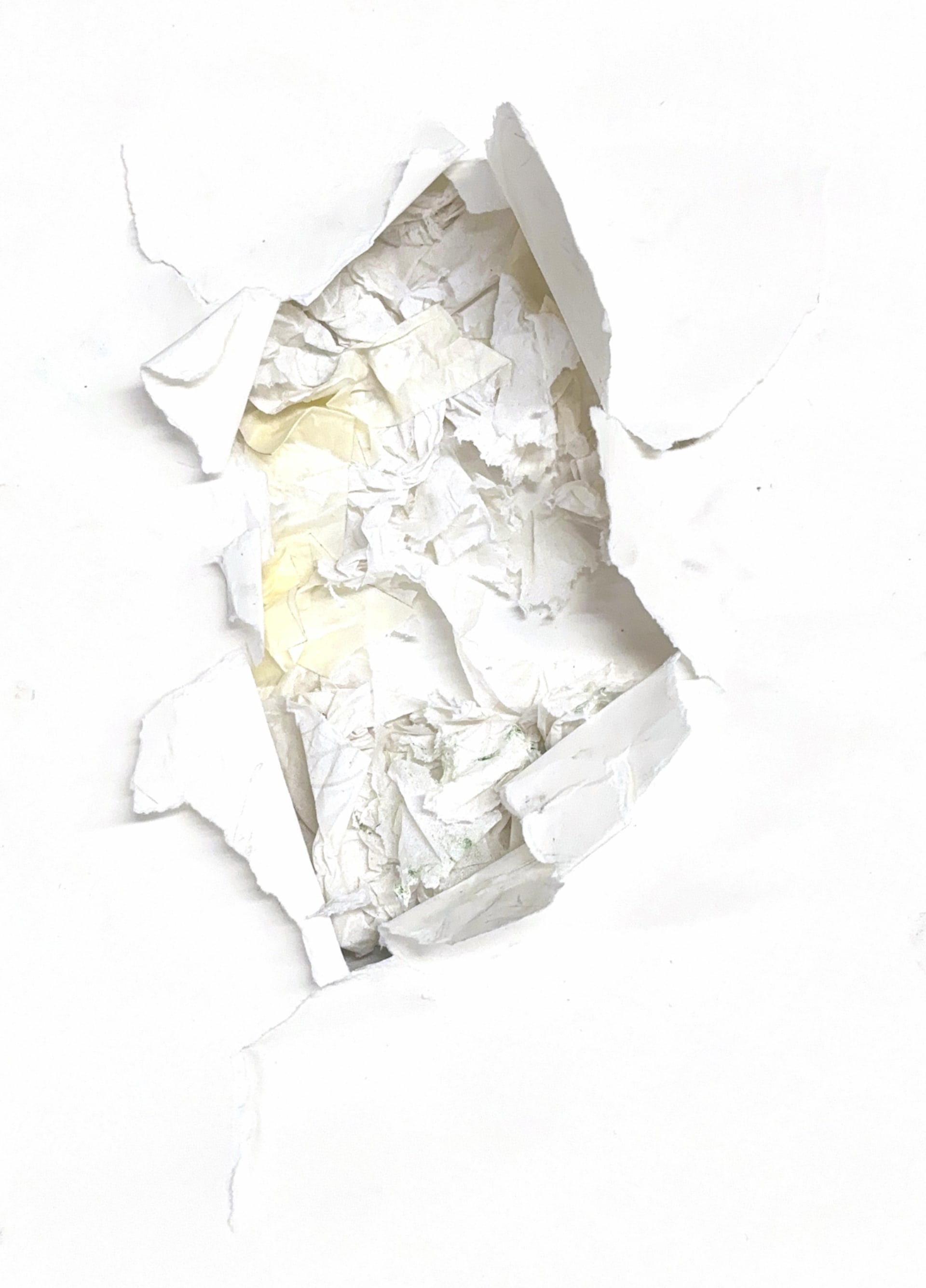 The paper is pierced in the middle, revealing the textured layers of tissue and masking tape.