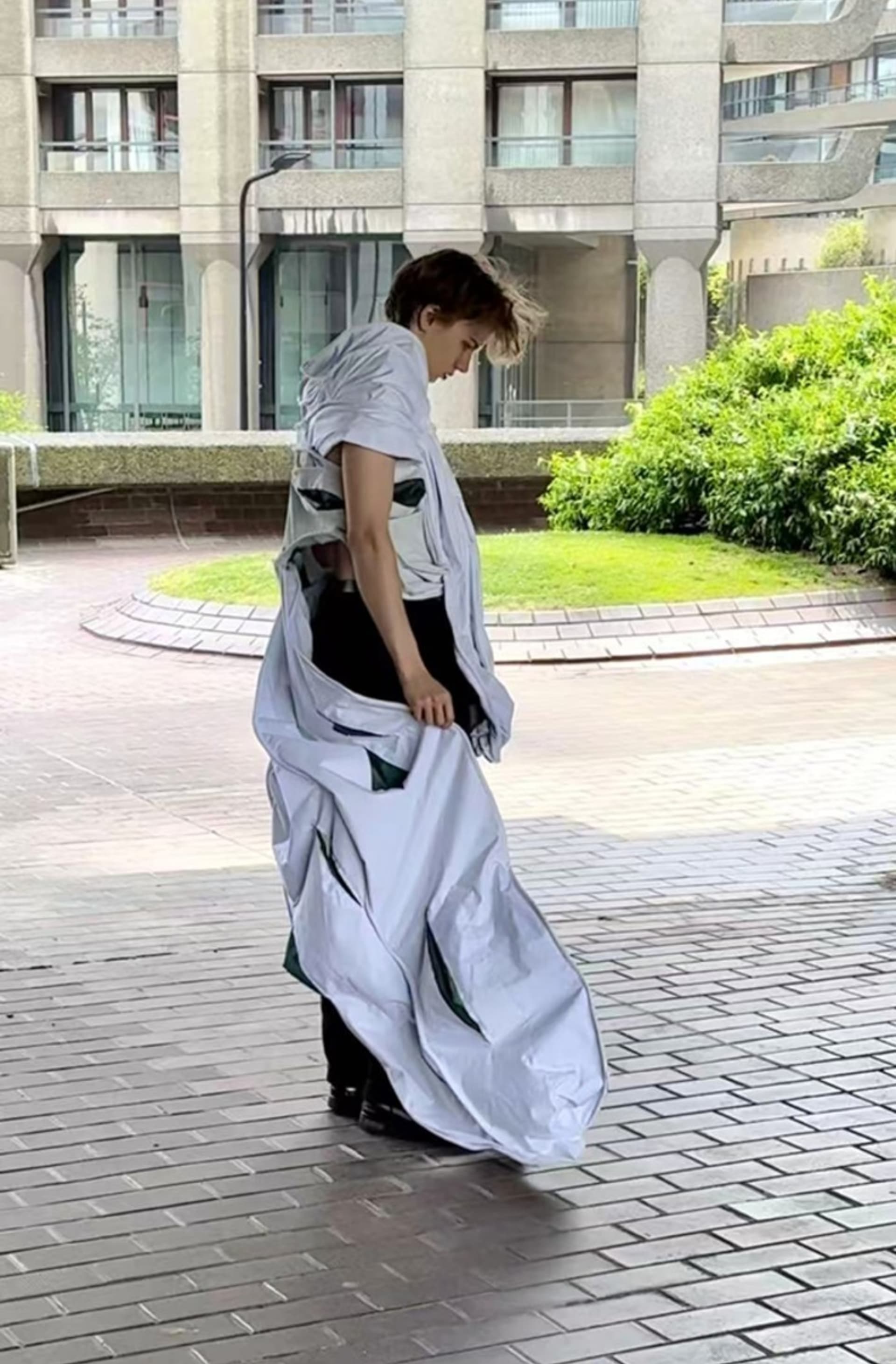 Man standing sideaways in pocketed wired pleated garment