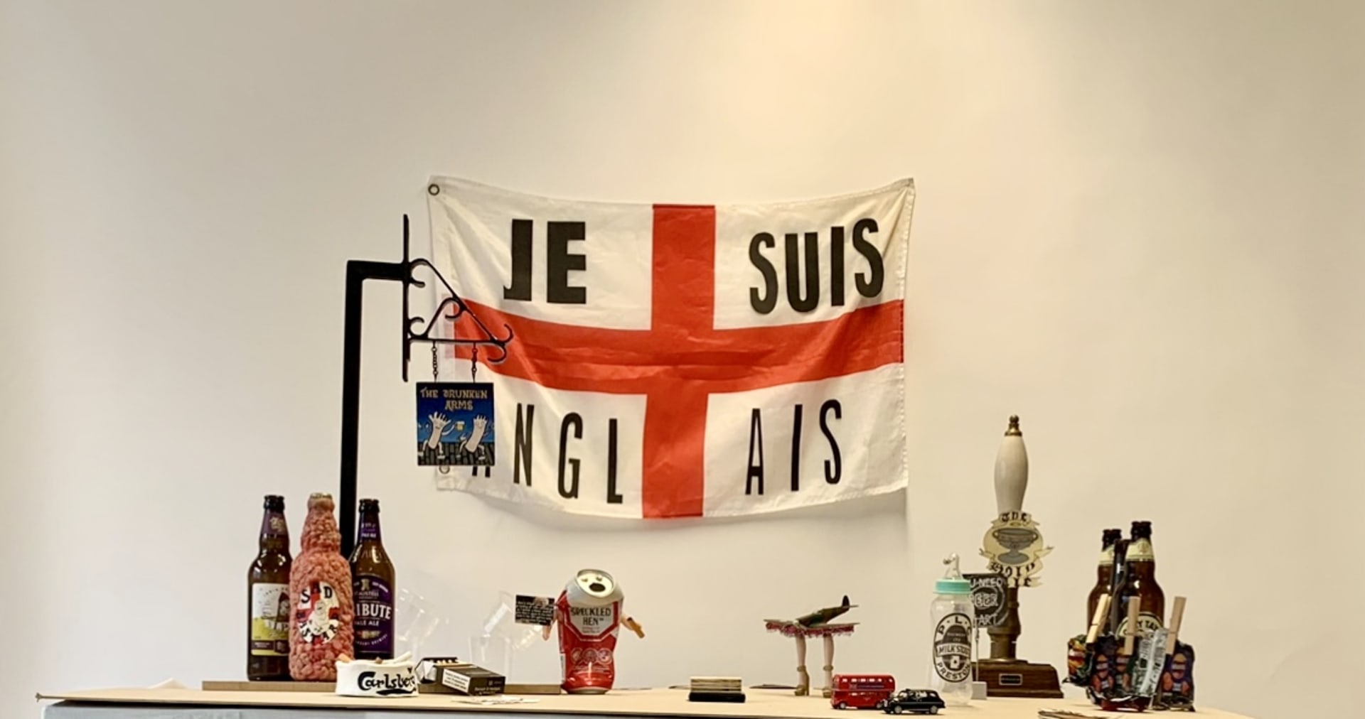Pub set with England flag in background stating "Je Suis Anglais" and pub sign named The Drunken Arms