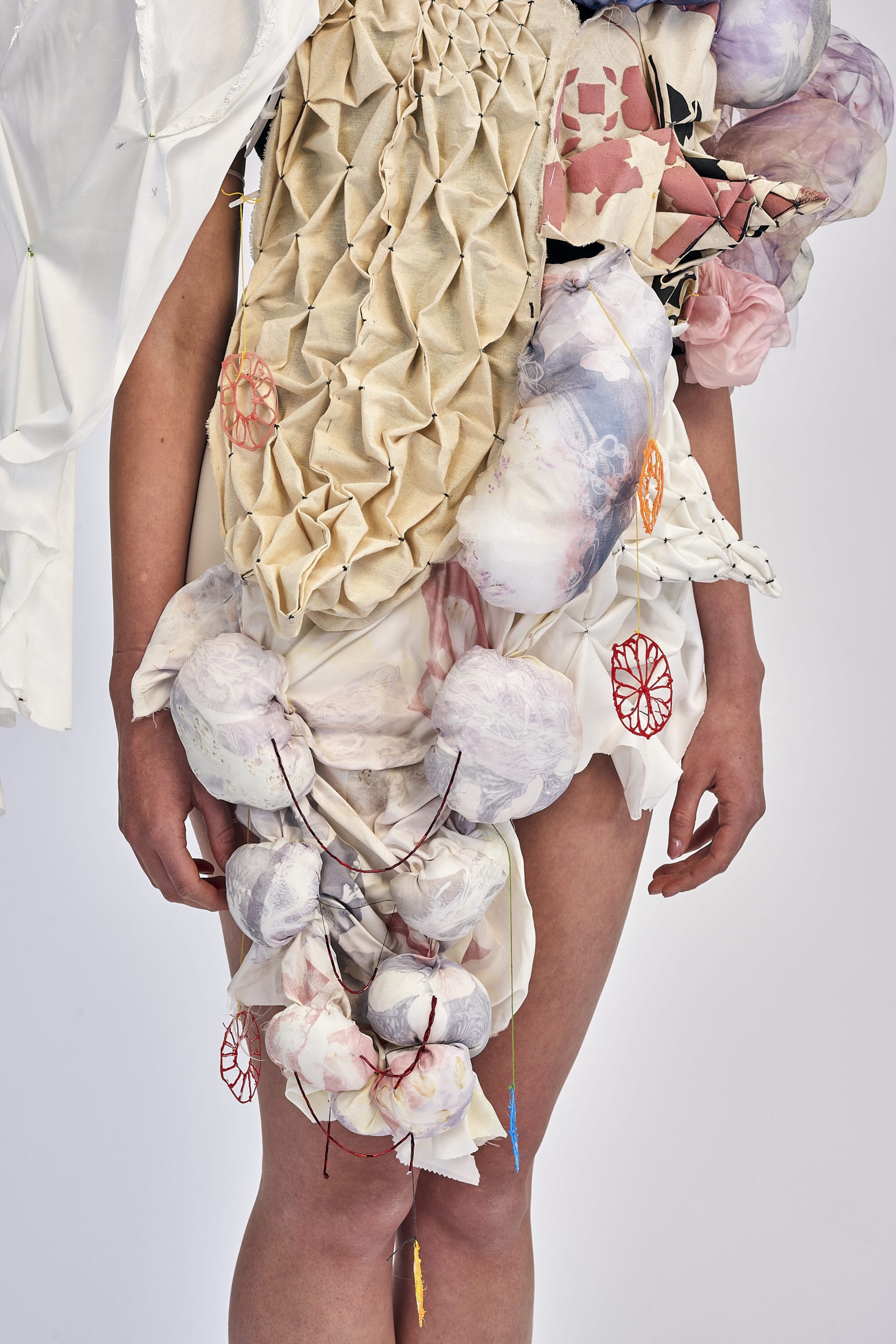 close up showing final garments a textiles collection of honey comb smocking, heat fabric manipulation, resist printing, radial smocking.