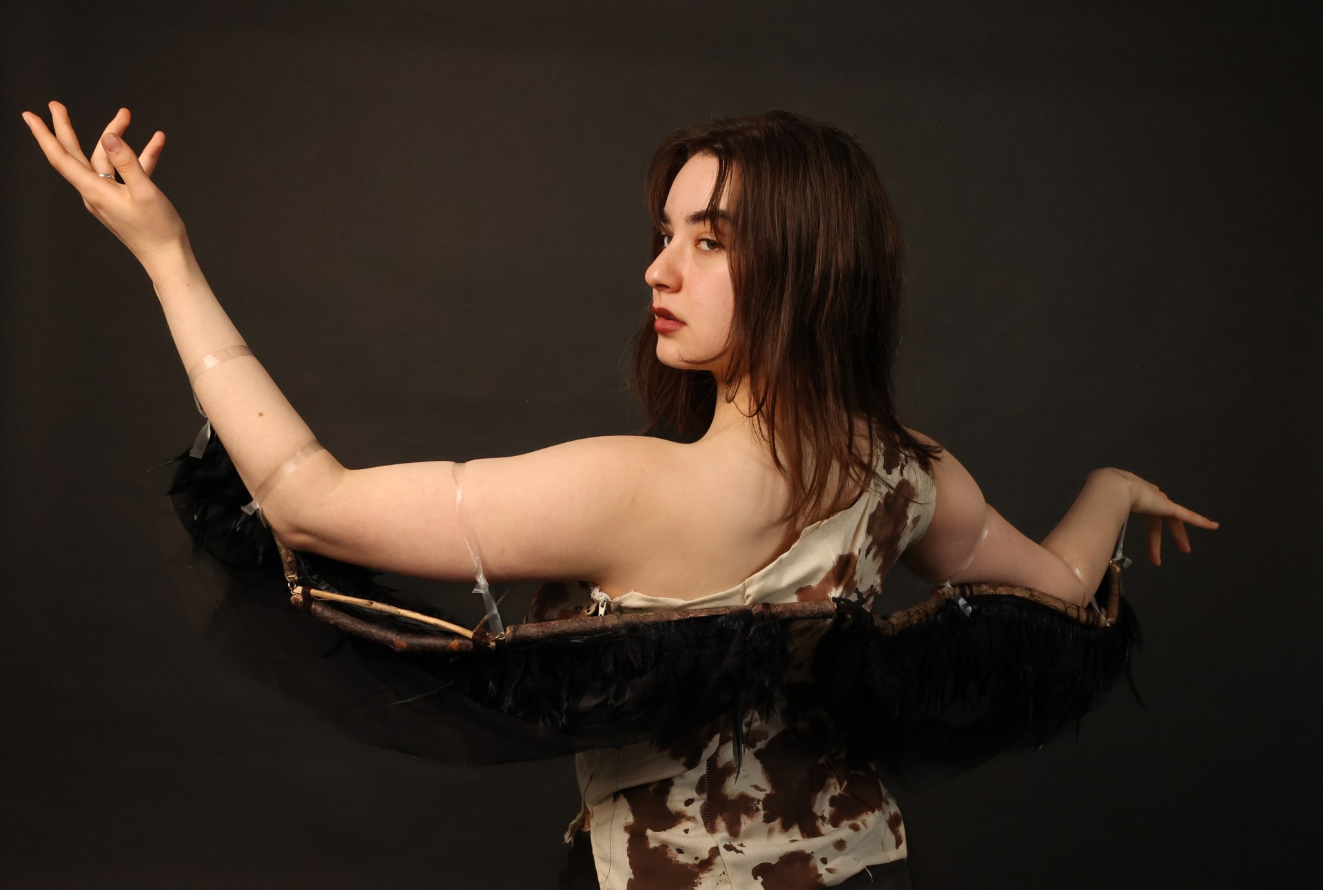 Close up of a woman wearing a costume that resembles a bird hatching out of an egg. Her back is shown which emphasises the wings.