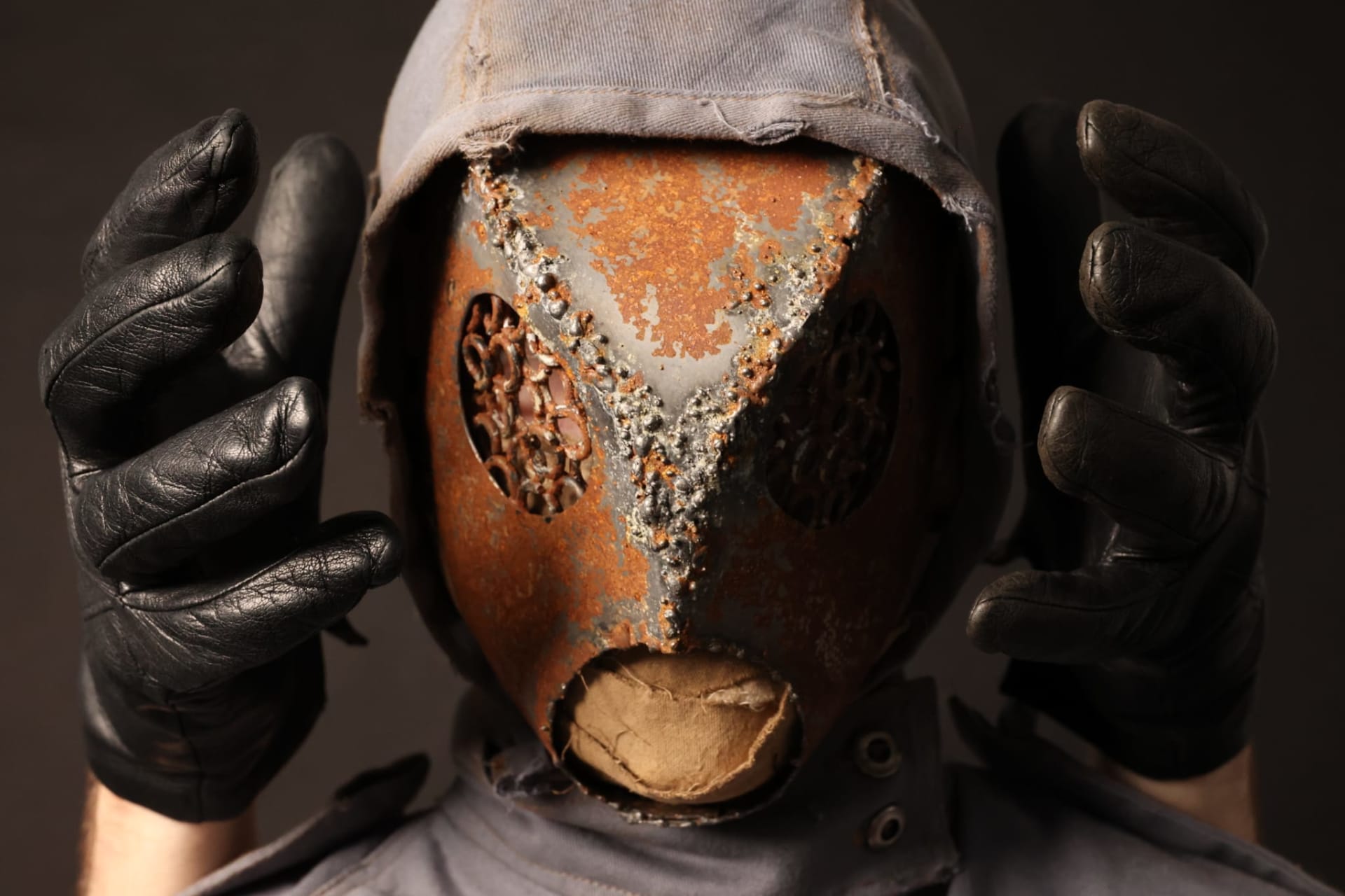 Close up image of the metal mask with hands surrounding