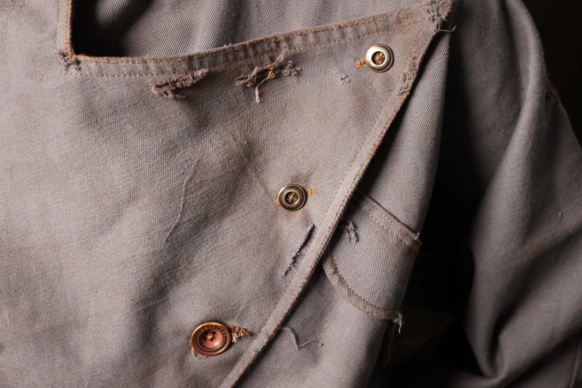 Close up image of detail work including evidence of wear and mending of the buttons and fabric