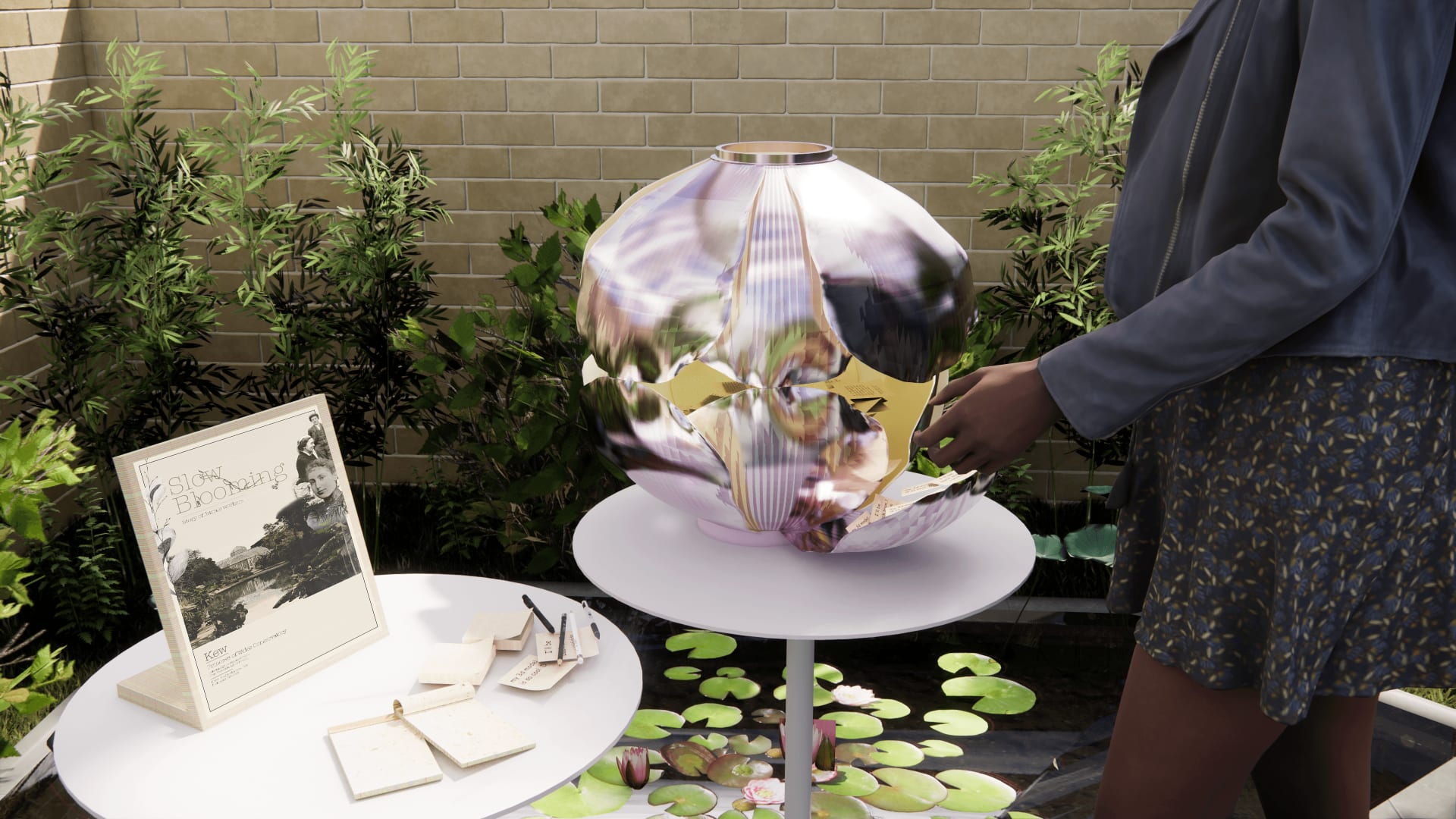 Green pond area with a person observing the metallic sculpture on a white pedestal table 