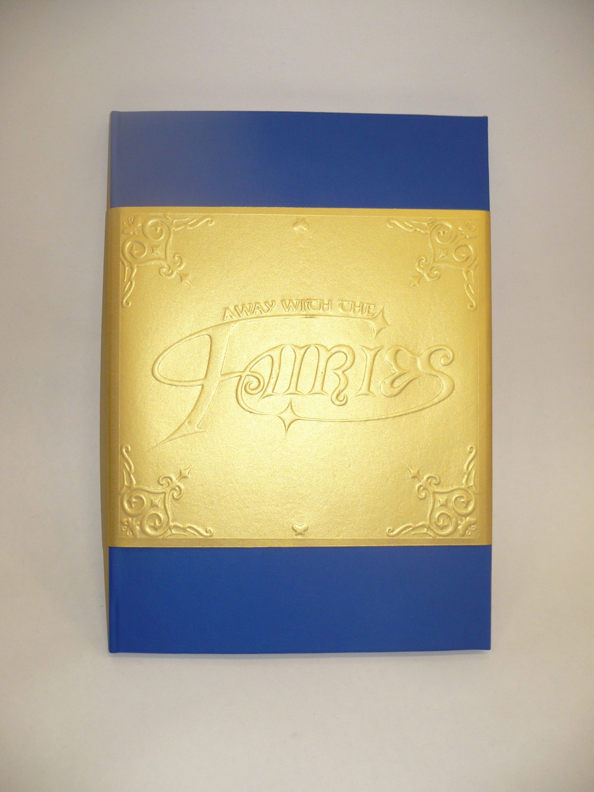The front cover of 'Away With The Fairies'. The dust jacket features an embossed logo and gothic ornamentation.