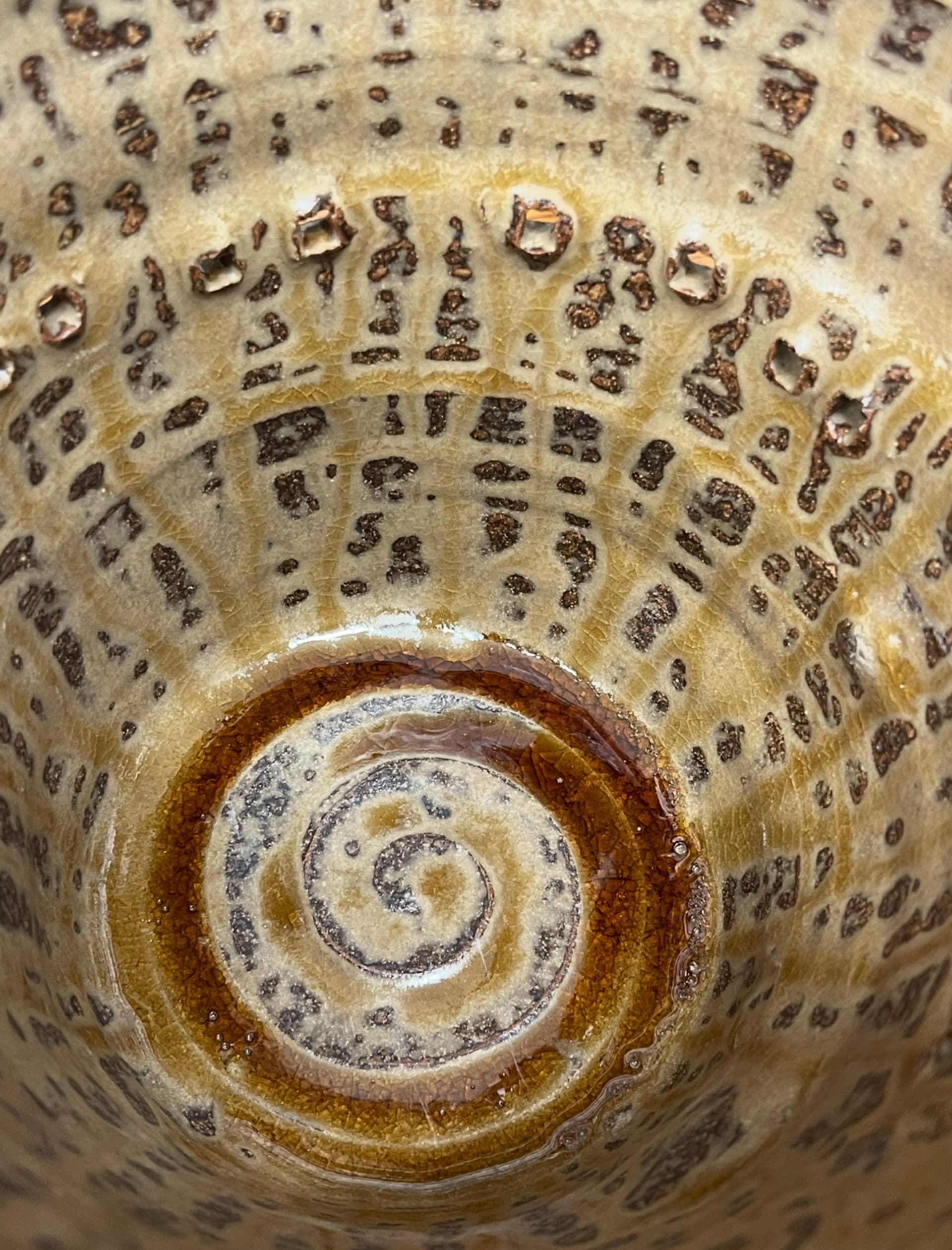 a ceramic glaze made from oyster shells and oak ash, light caramel brown colour with drippy glossy streaks that pool down into the base