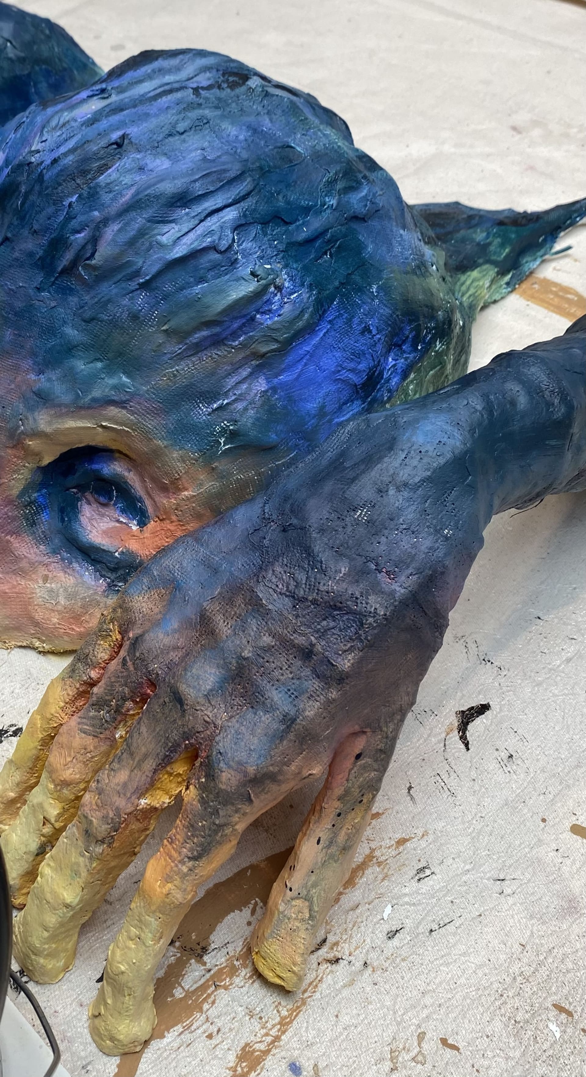 close up photo showing the range of colour used to paint sculpture. Hues ranging from dark blue and purple to orange and yellow like a sunset.