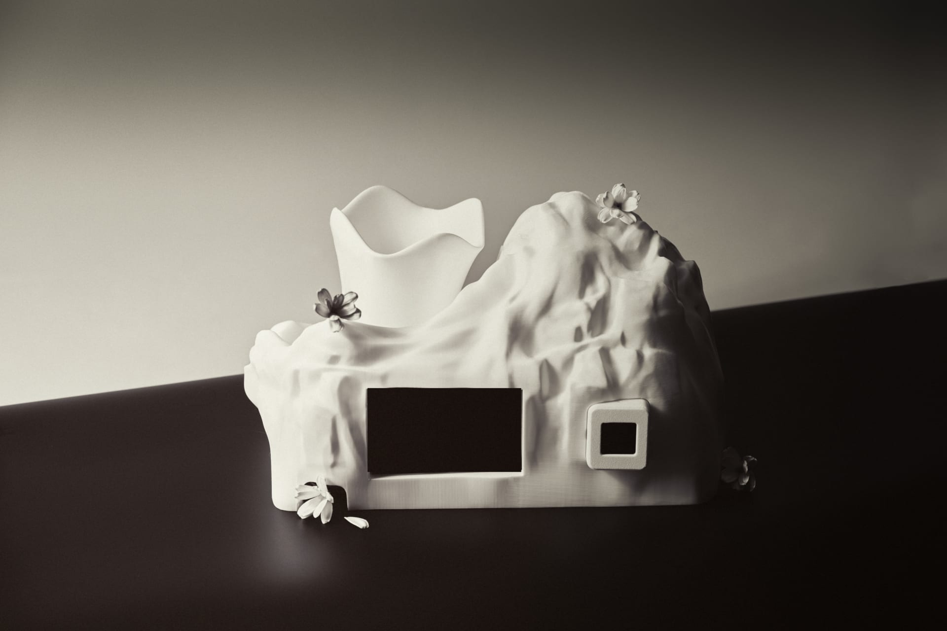 A white 3D-printed sculptural planter shaped like a mountain, with smooth, flowing textures resembling natural rock formations.