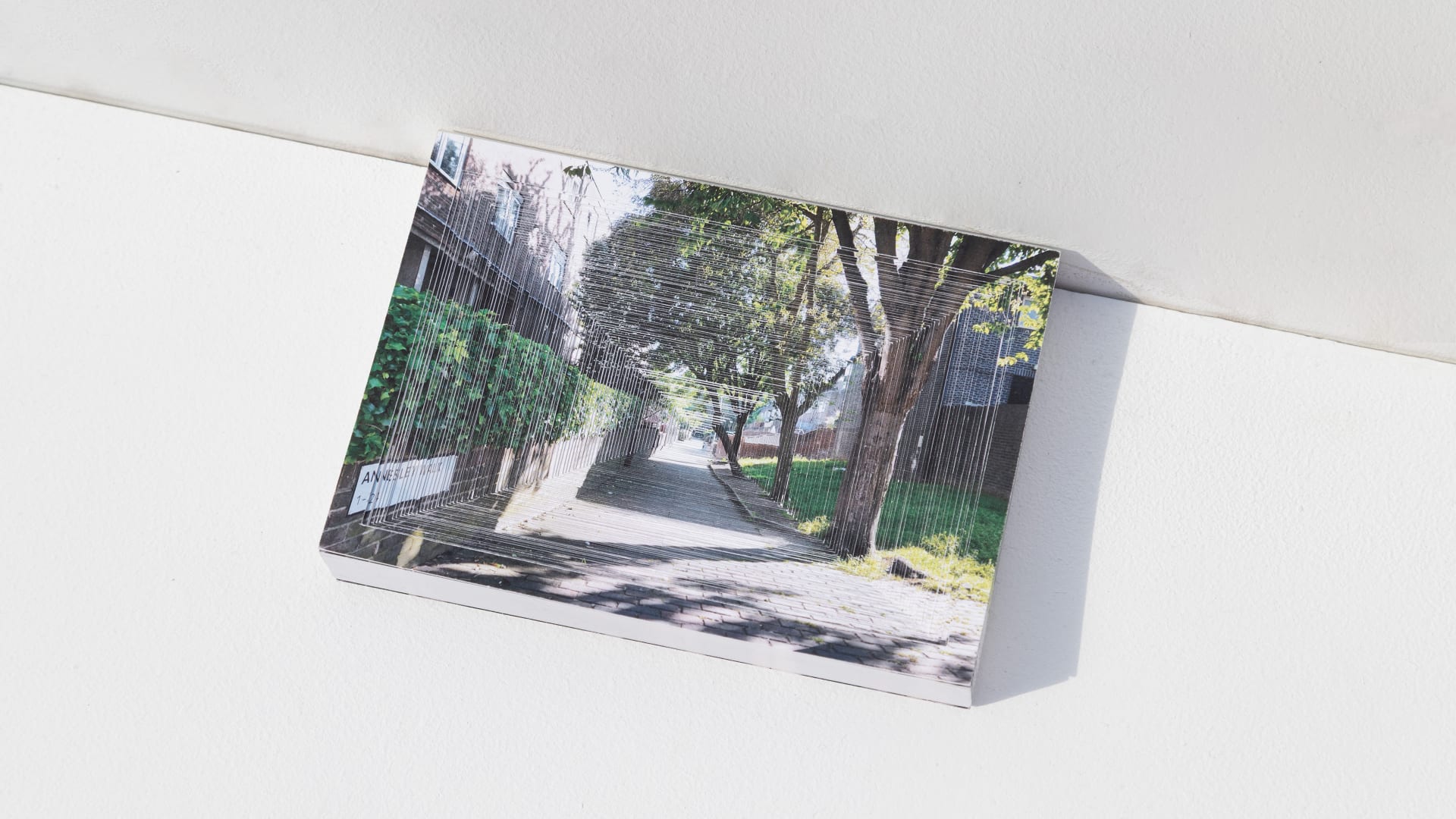 A book with a central cut-out aligns a perspective street view, creating a tunnel-like effect that evokes strong spatial convergence.