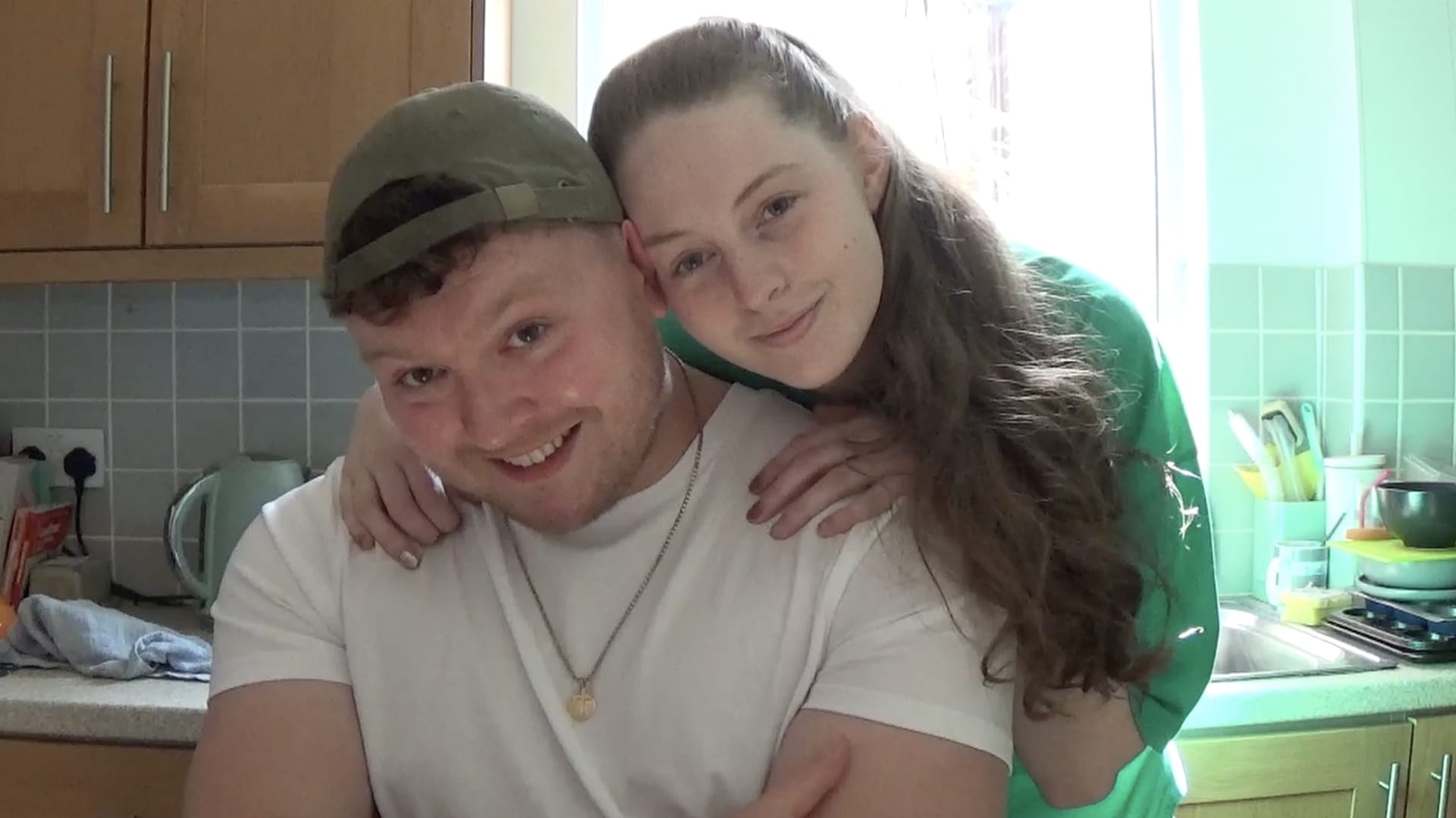 The happy couple smiles at the camera after the man receives a gold chain as a gift from his partner.
