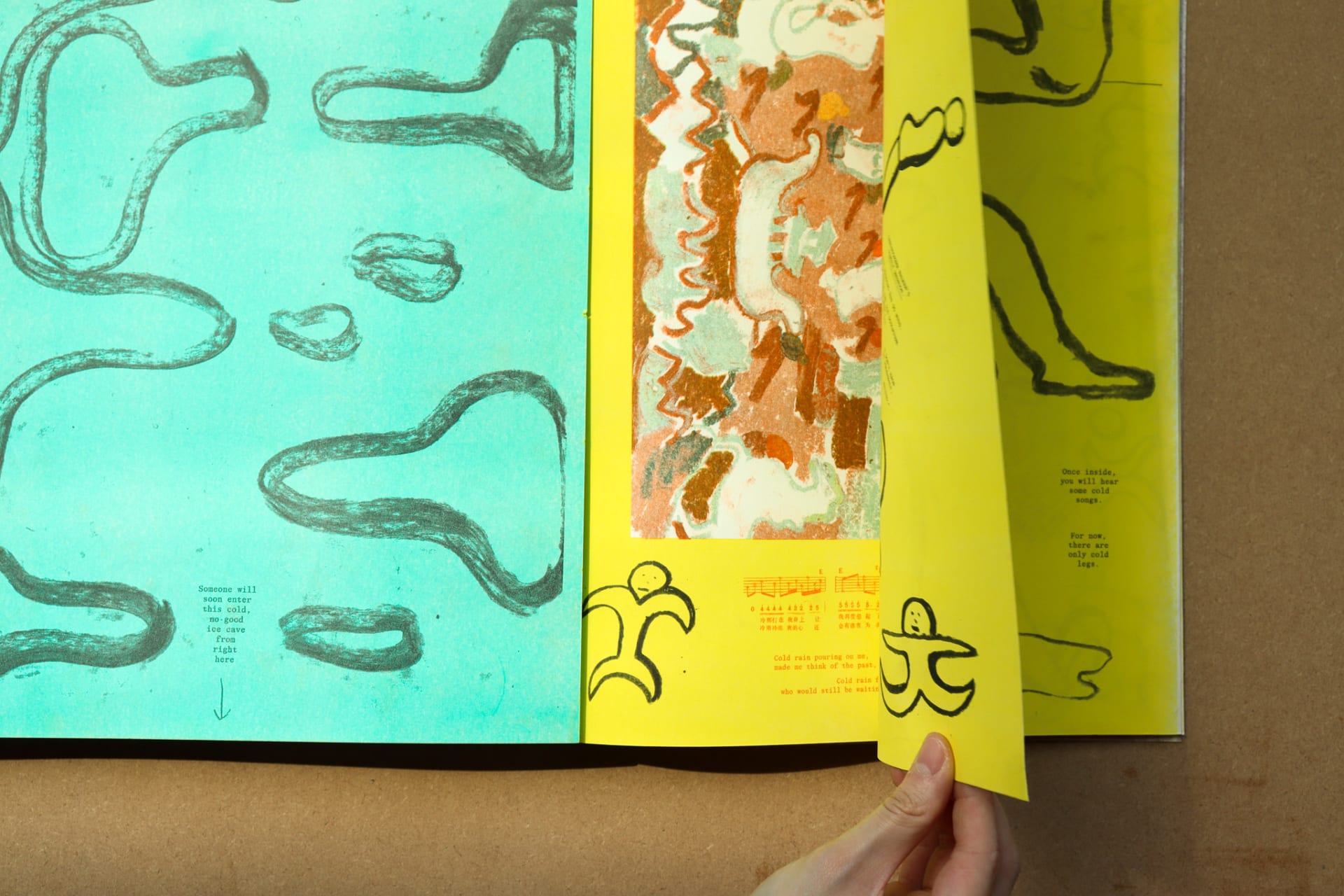 A hand flips a page, revealing a drawing of ice sculptures underneath