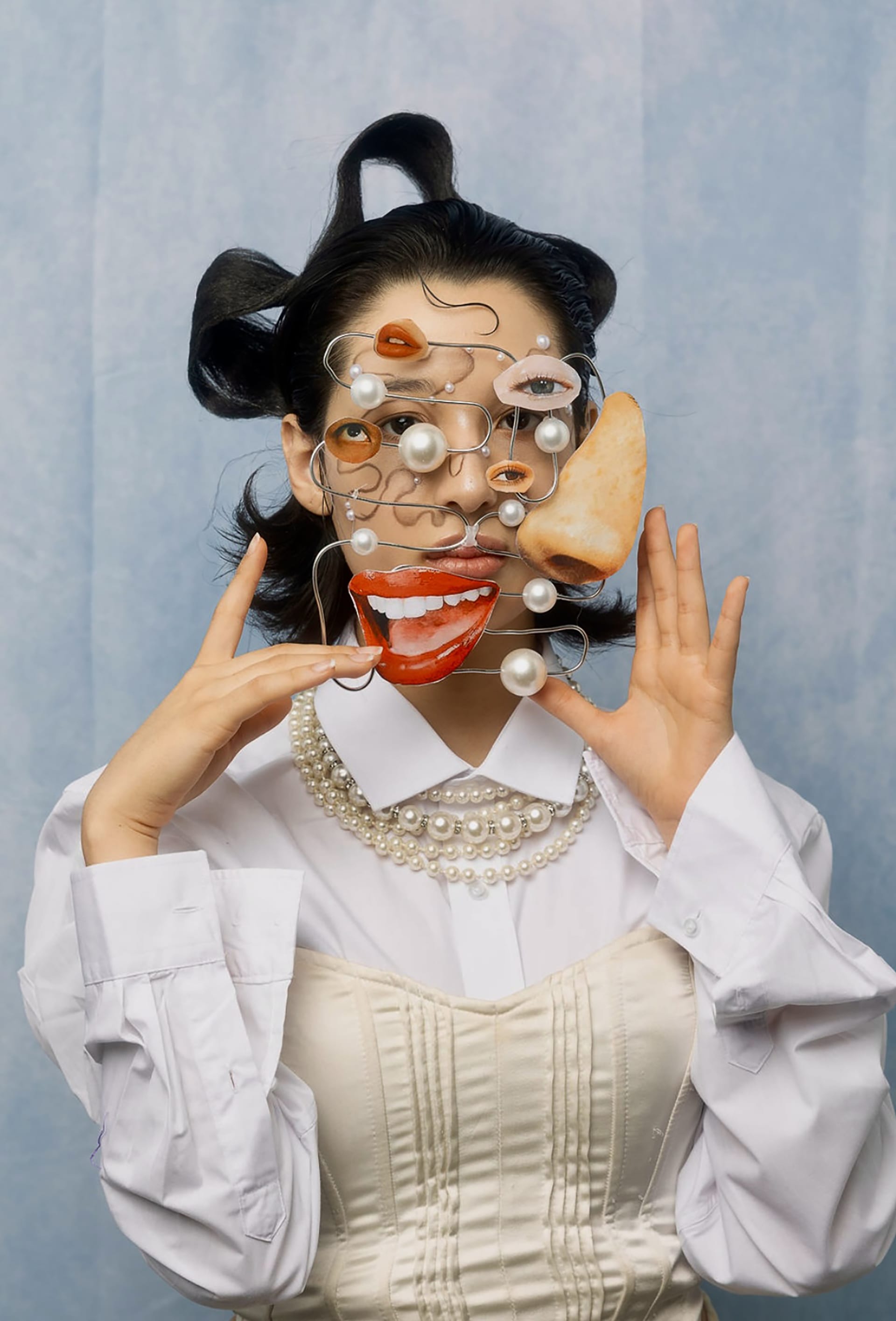 A girl is holding a bent wire object close to her face.