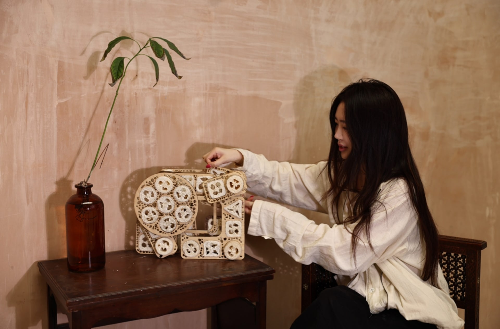 Designer interacting with a modular loofah structure, exploring new forms through low-tech, glue-free connections.