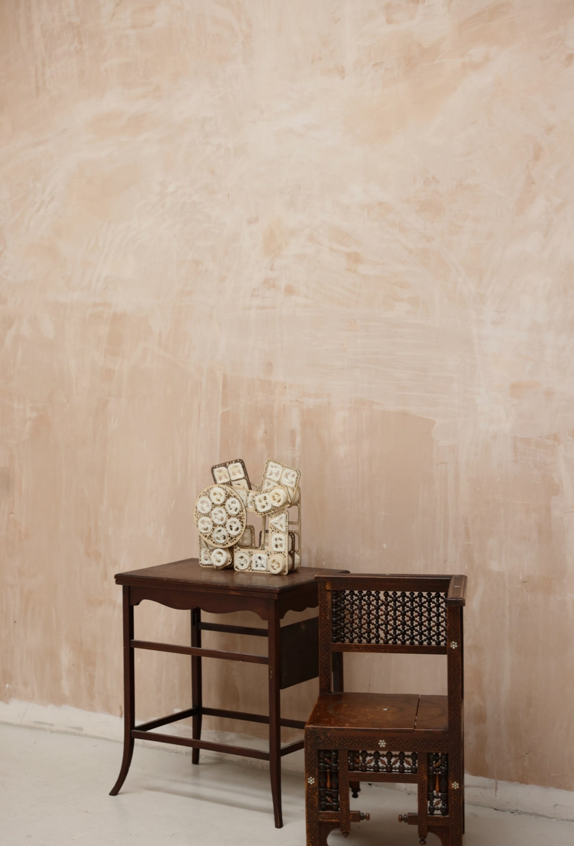 A loofah-based modular structure displayed on a wooden table, highlighting material contrast and spatial presence in a calm setting.