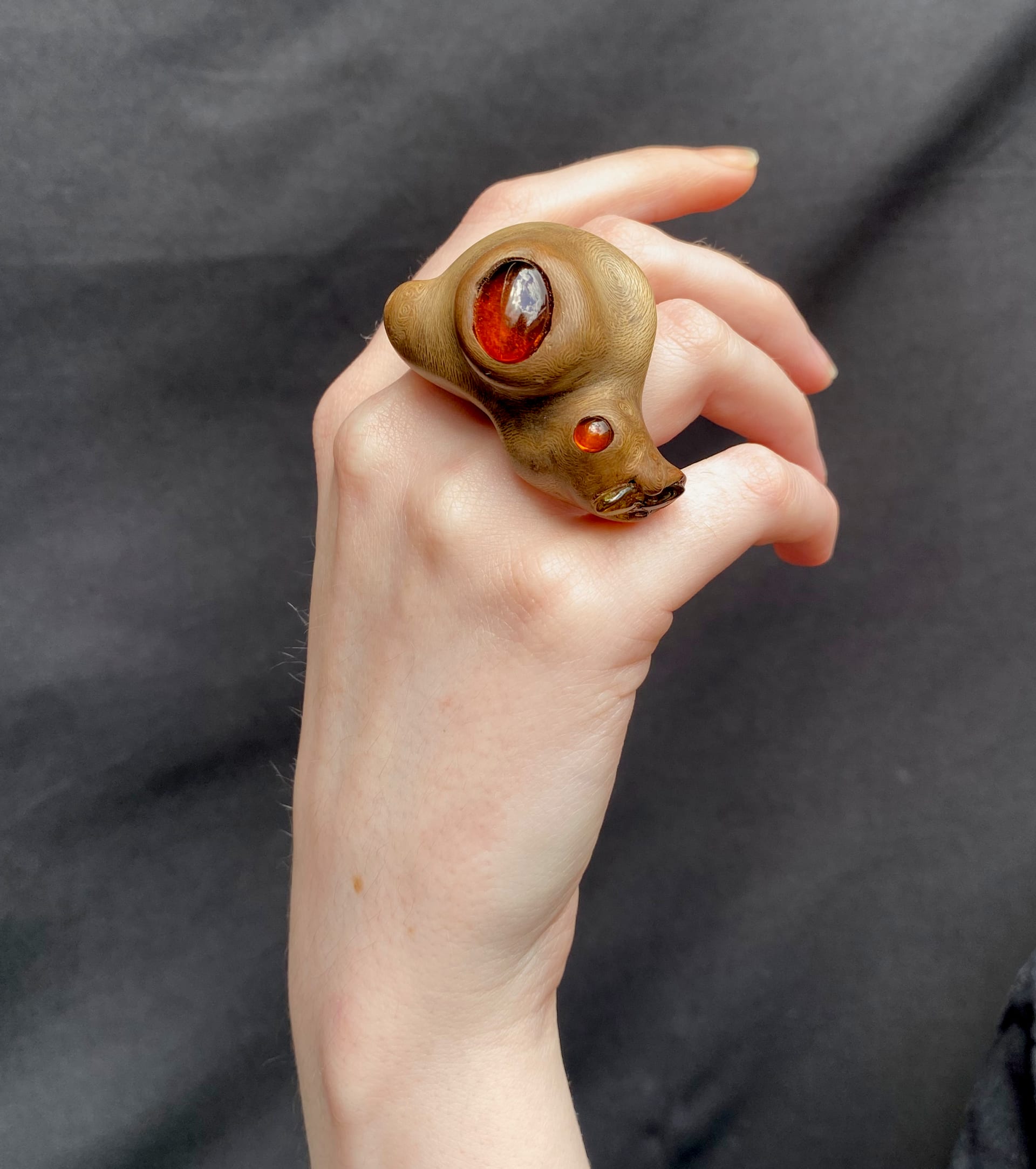 A ring with a fluid bulbous shape. It has a large amber set in the centre within a branch scar and two smaller ambers set on the right. 