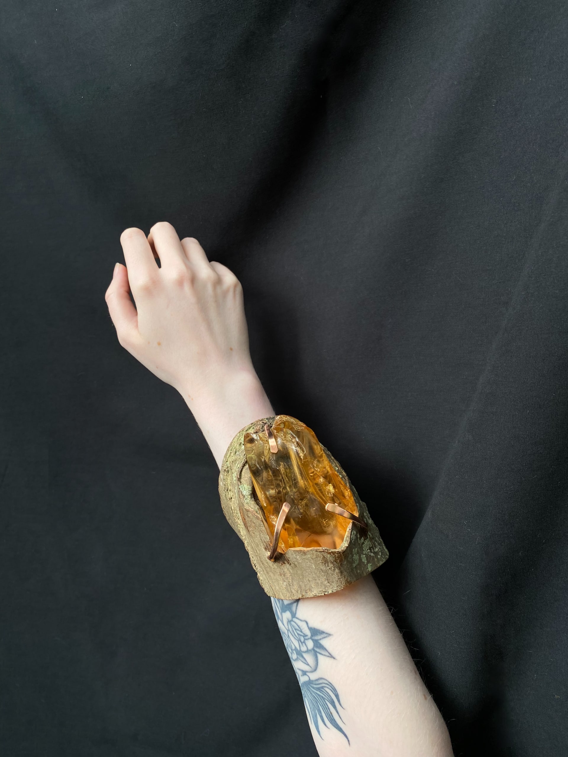A large cuff with a large chunk of amber set in copper claw setting