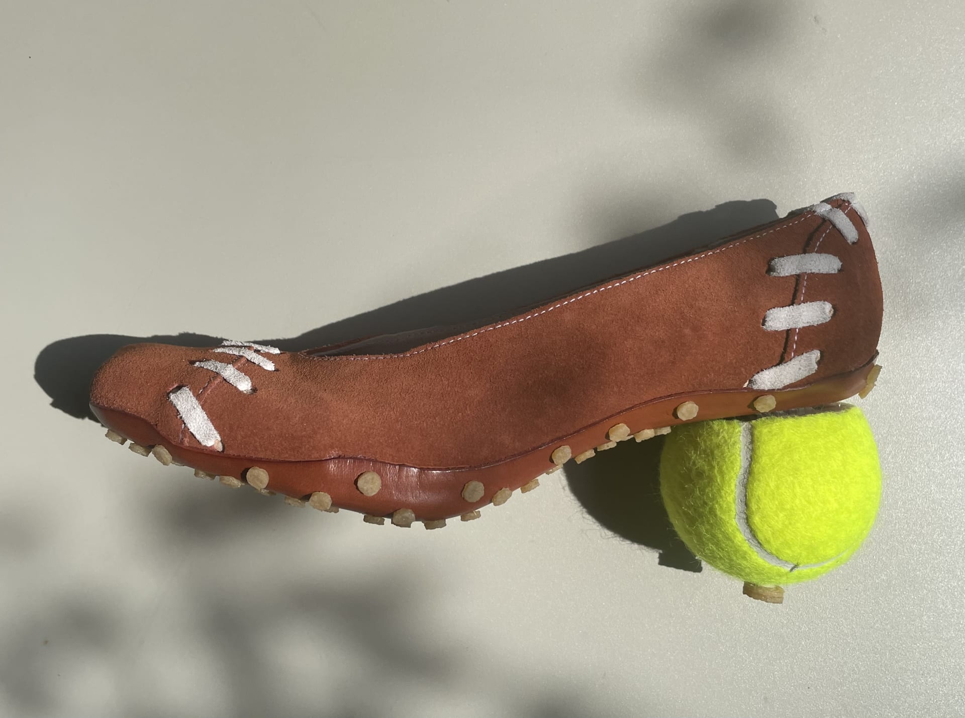 clay coloured suede court shoe, with contrasting white stitching. Has a tennis ball heel.