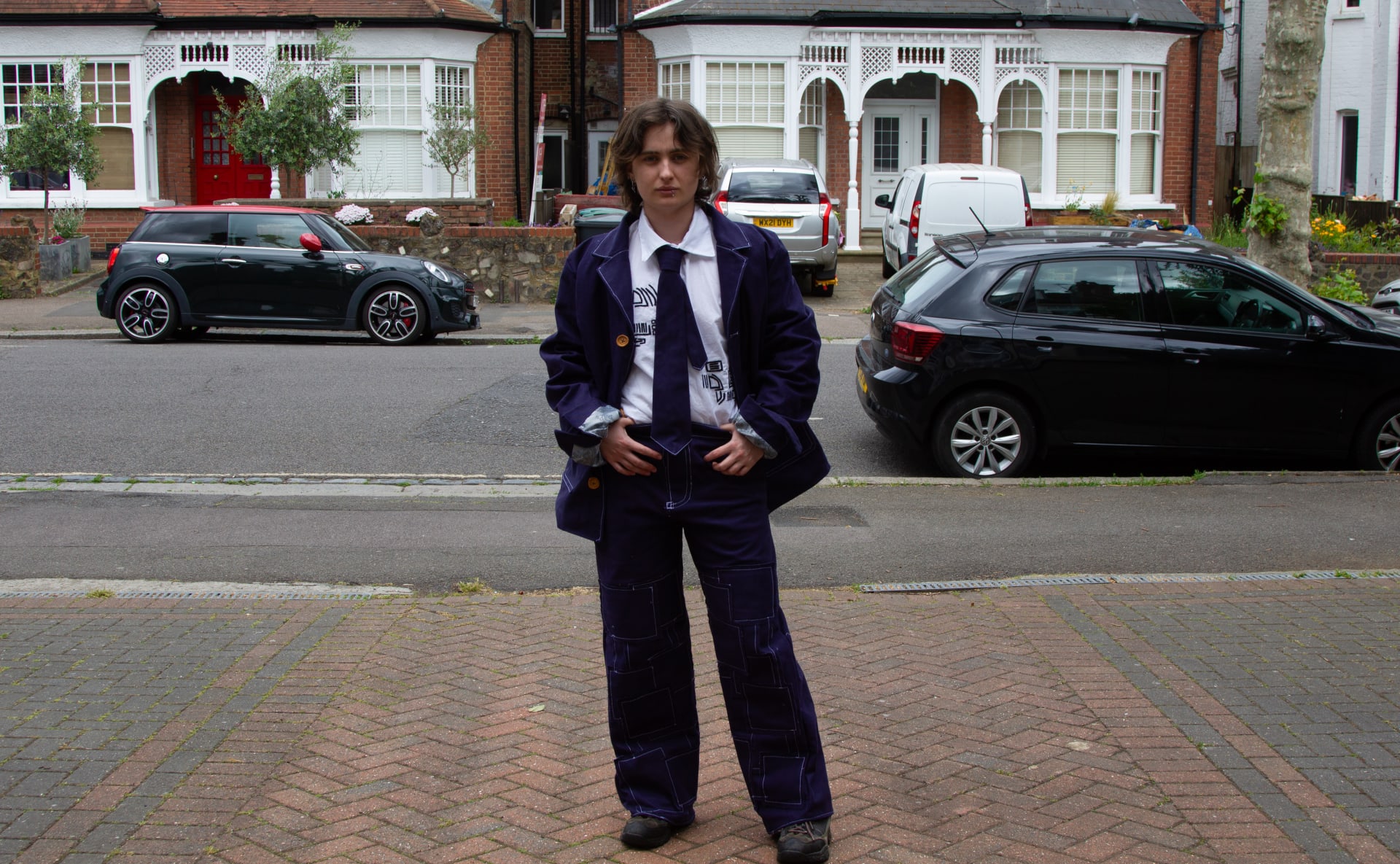 Navy blue suit made from heavy twill cotton with contrasted white stitch embellishments and a grey paisley lining on both the suit jacket and tie 