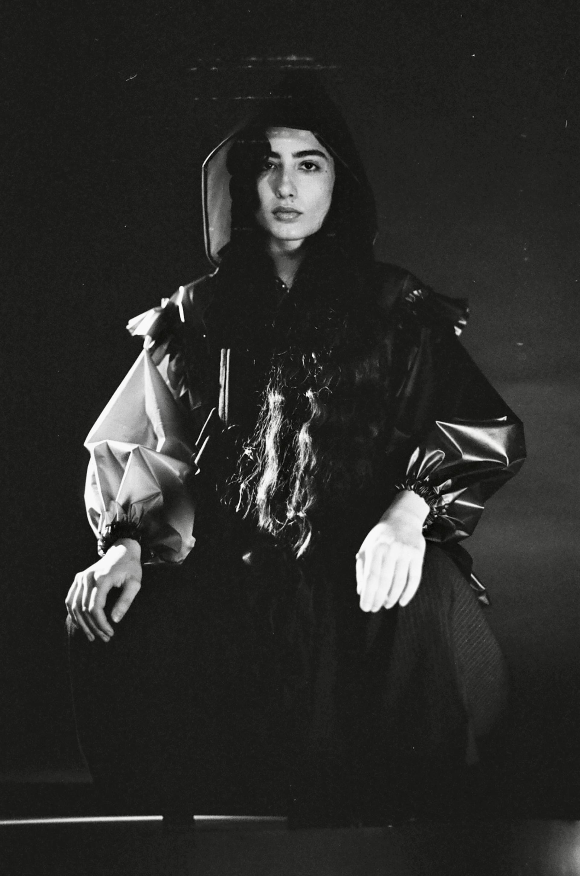 Model wears look PVC frill hoodie and pinstripe pleated trousers.