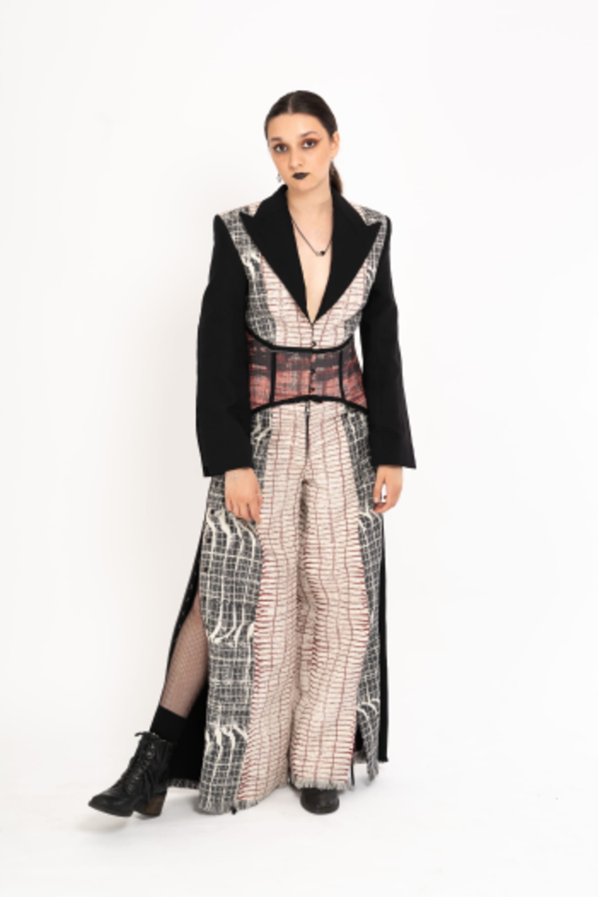 Female model wearing a corseted jumpsuit. Self designed Hainsworth fabric, featuring graphic black, white and red design.