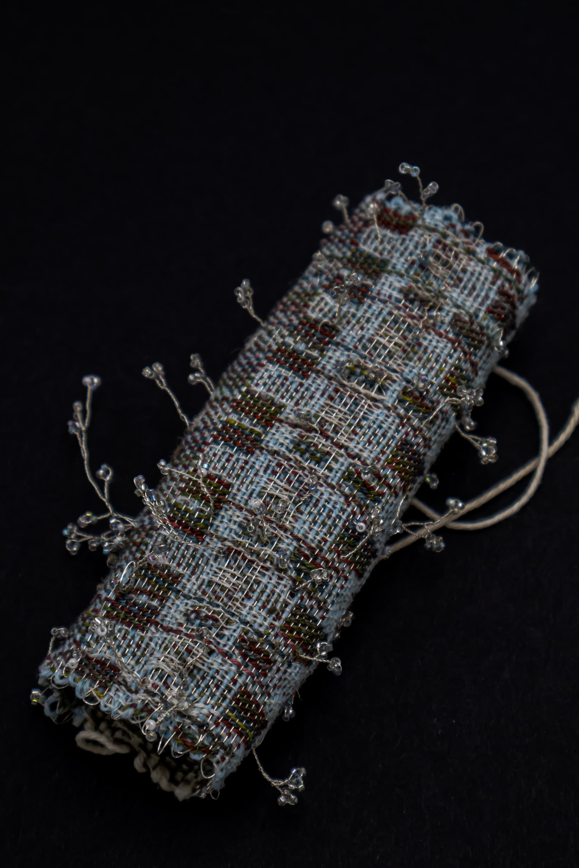 A double cloth textile featuring direct-dyed Tencel warp and pineapple fiber warp, with Pinayarn, Tencel, and hand-crafted wire-and-jewel floral forms