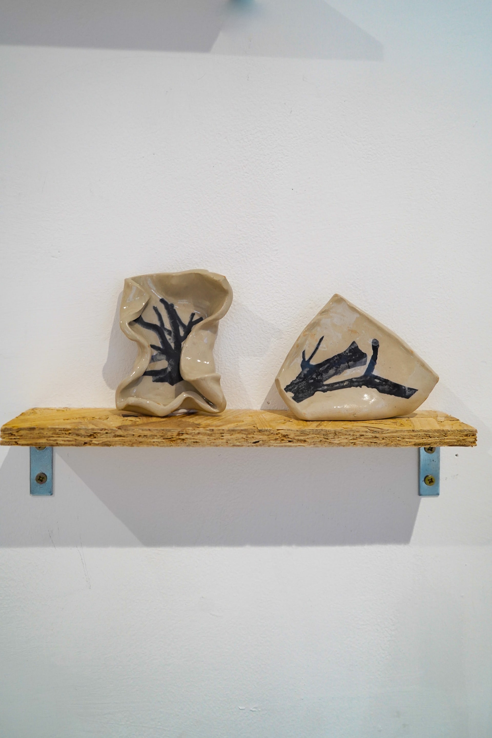 Two freeform curved tiles on a shelf, with black and white tree images set onto them