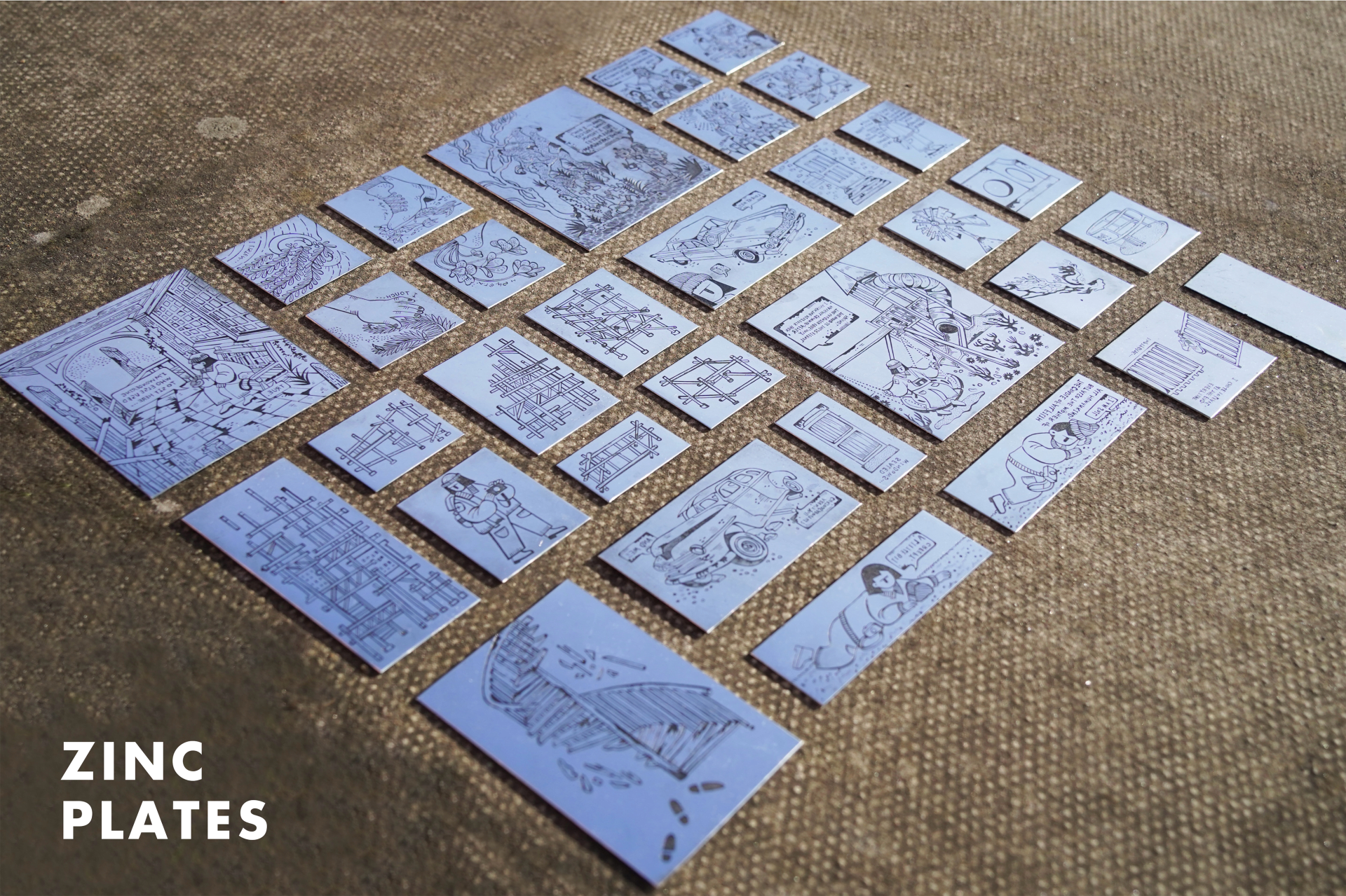 A series of printmaking zinc plates display on the ground.
