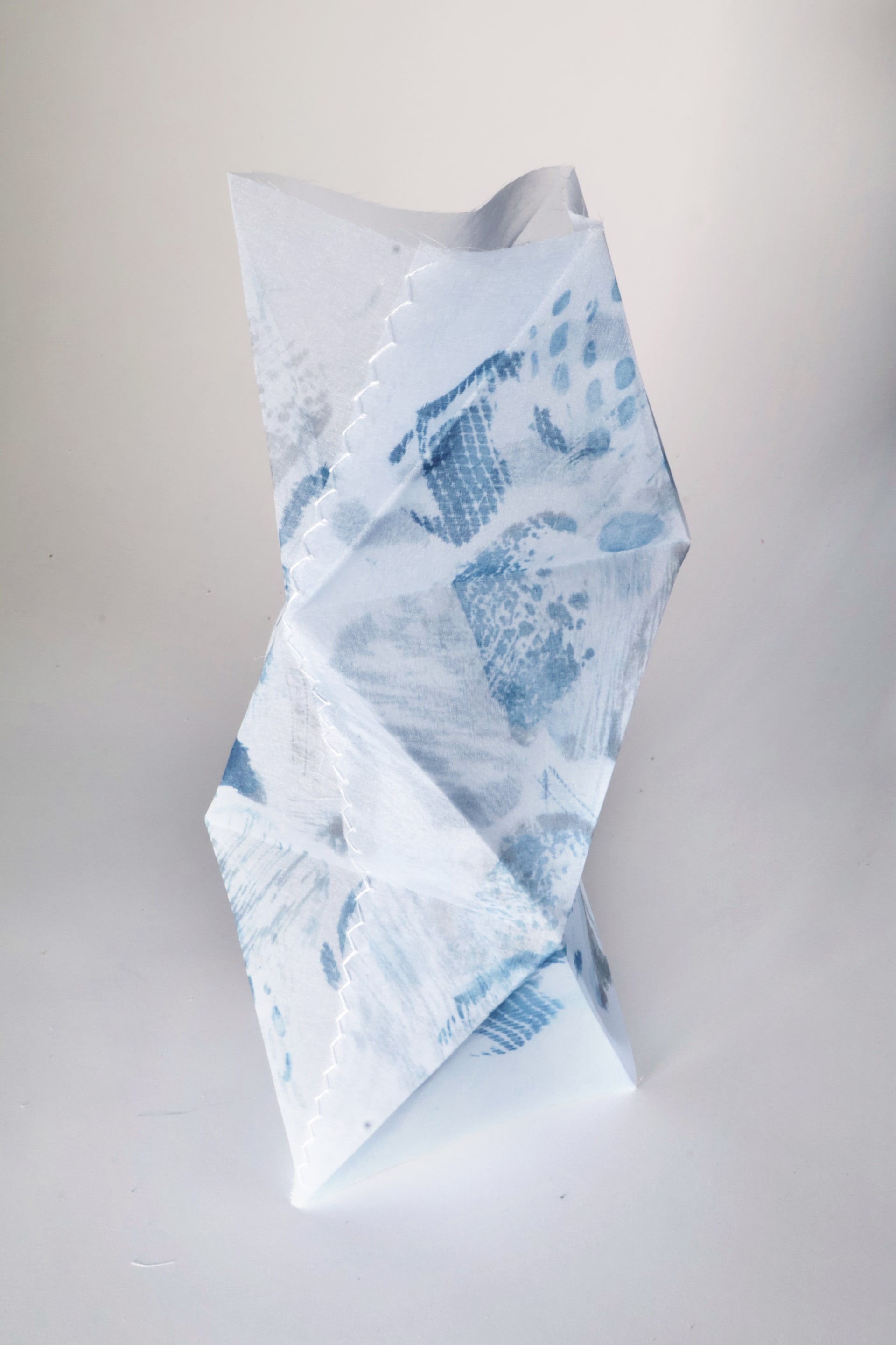 A freestanding 3D translucent textile with pale-blue abstract patterns, forming a twisting sculptural silhouette.