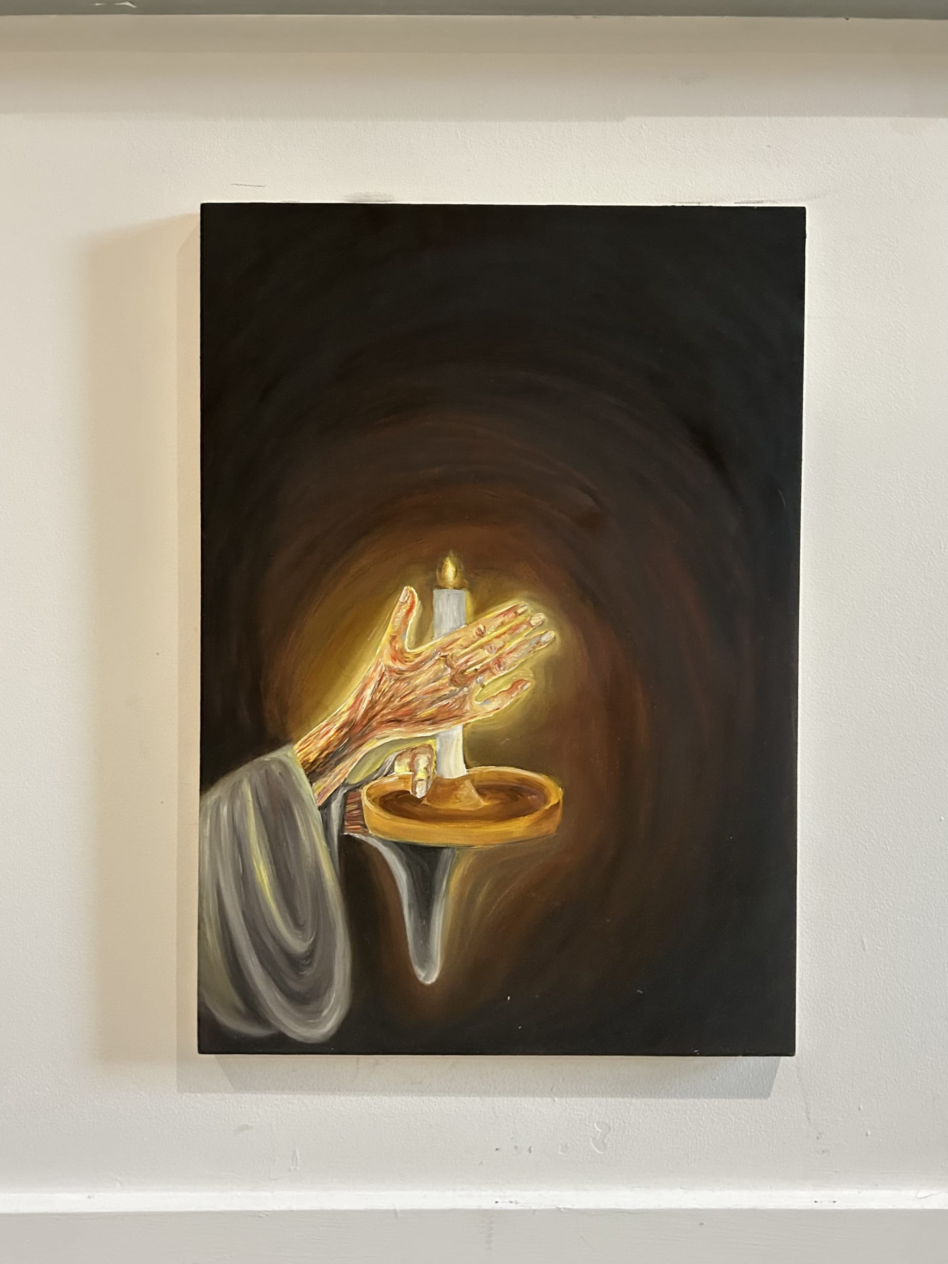 A hand reaches out from the left of the painting, holding a candle, shielded by her other hand, the painting is lit by this glowing light