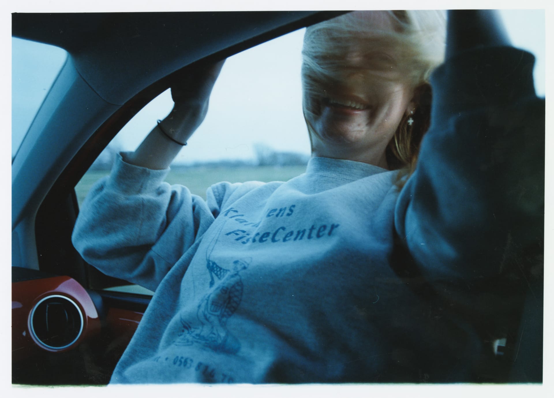 Photo shows girl leaning out a car window.
