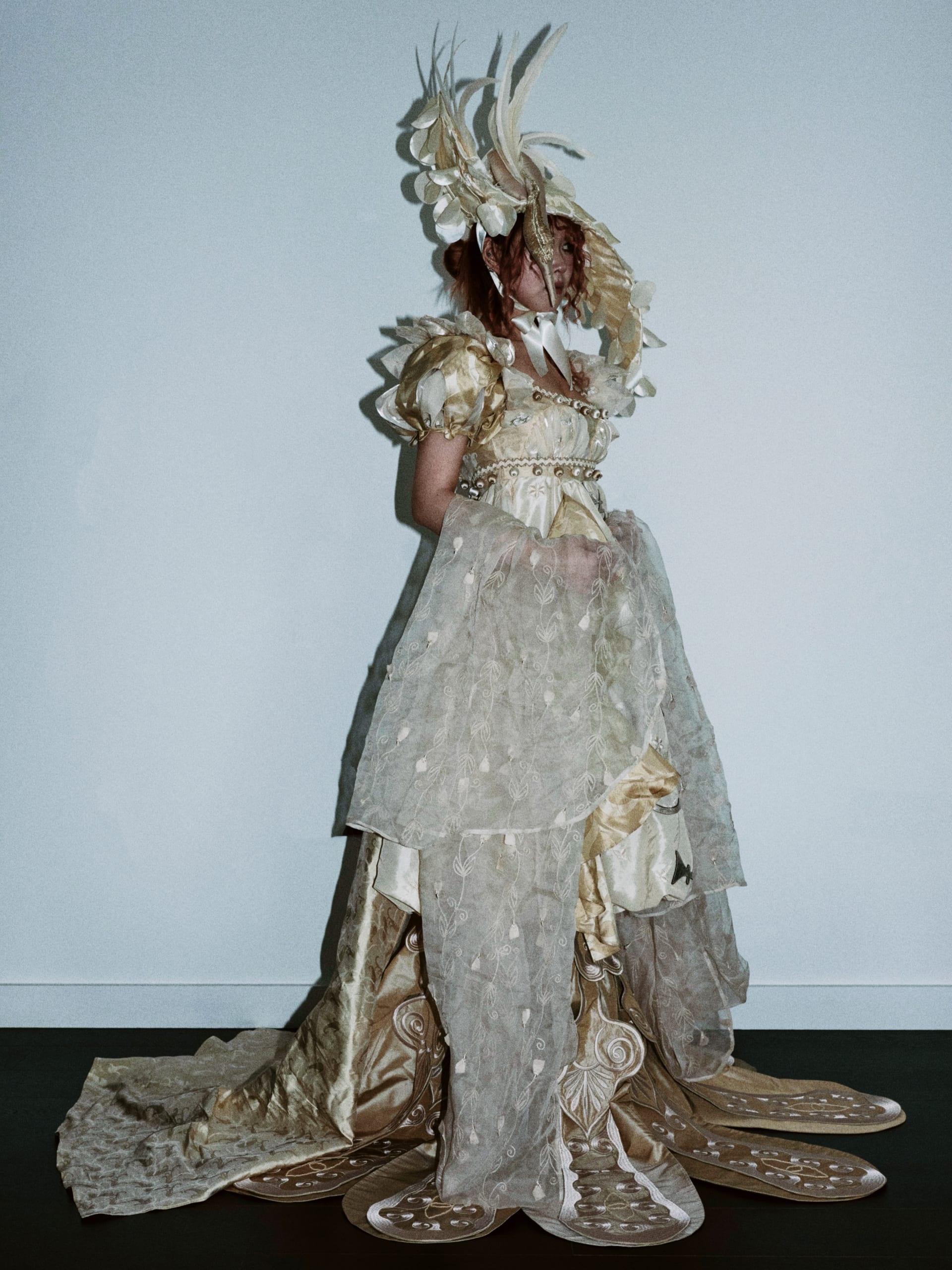 Regency-style  beige gown with leaf-decorated sleeves and embroidery hem. Hat with feathers and swan head detail.Embroidered organza draped from arms.
