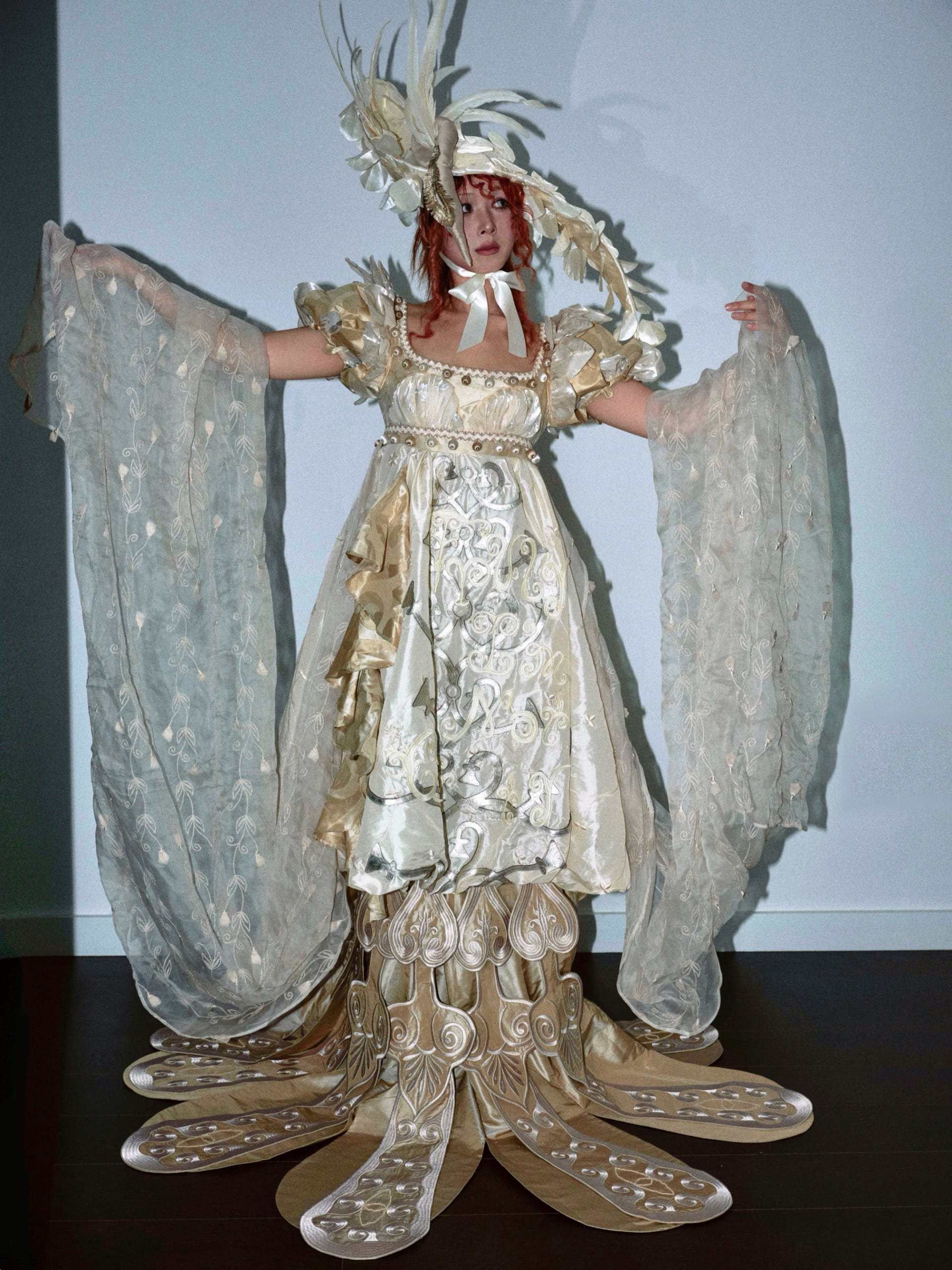 Regency-style  beige gown with leaf-decorated sleeves and embroidery hem. Hat with feathers and swan head detail.Embroidered organza draped from arms.