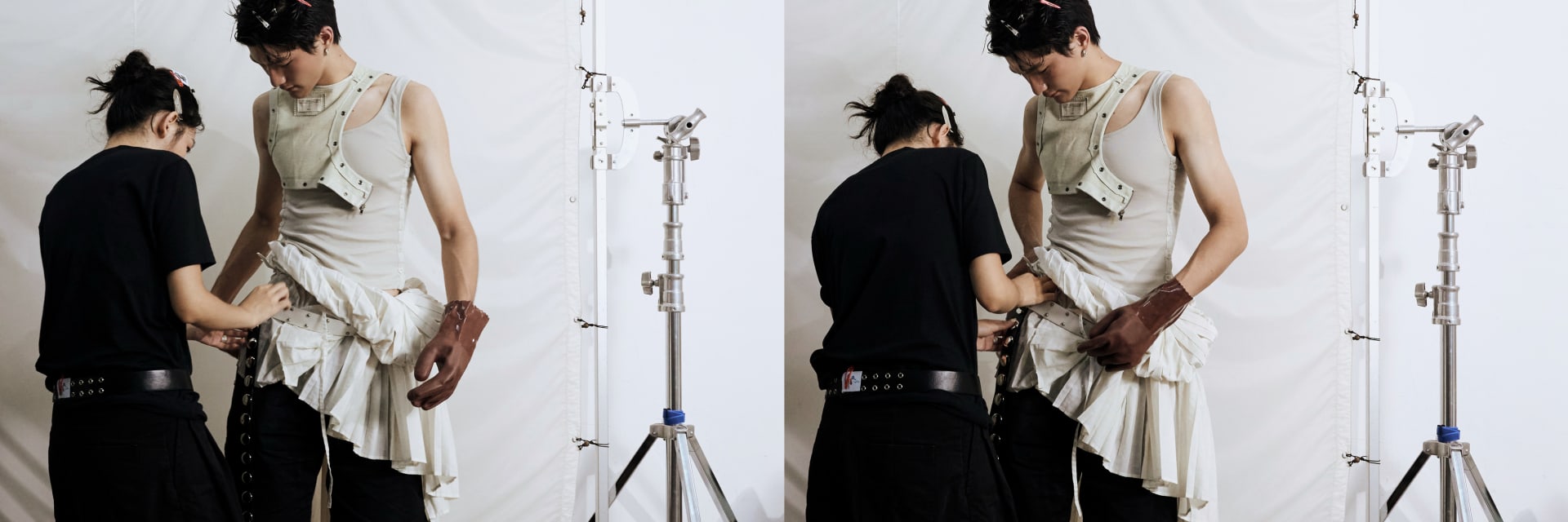 A stylist and model adjust garment details in the studio.