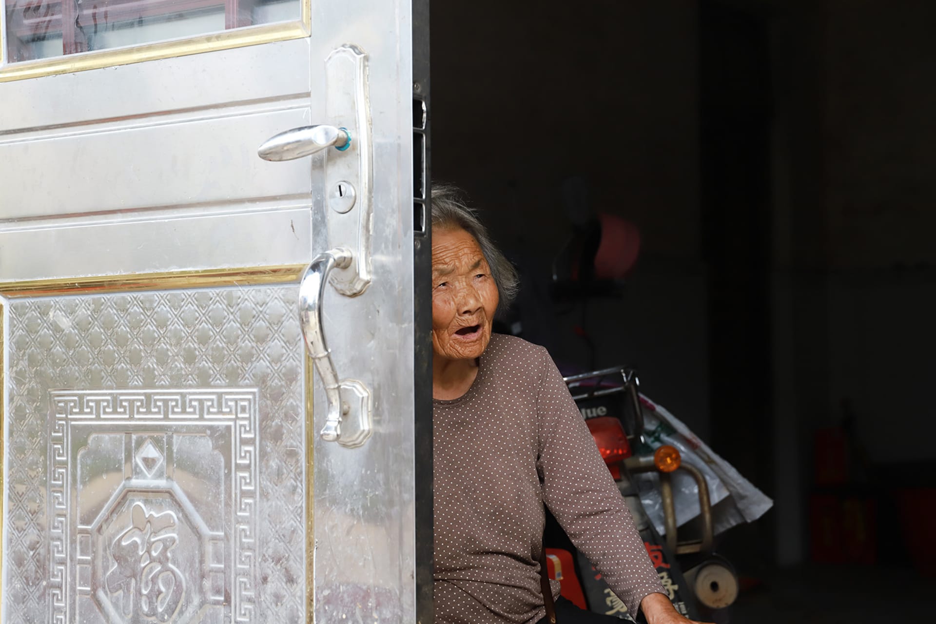 An elderly woman waiting longingly at her doorstep for her son's return.