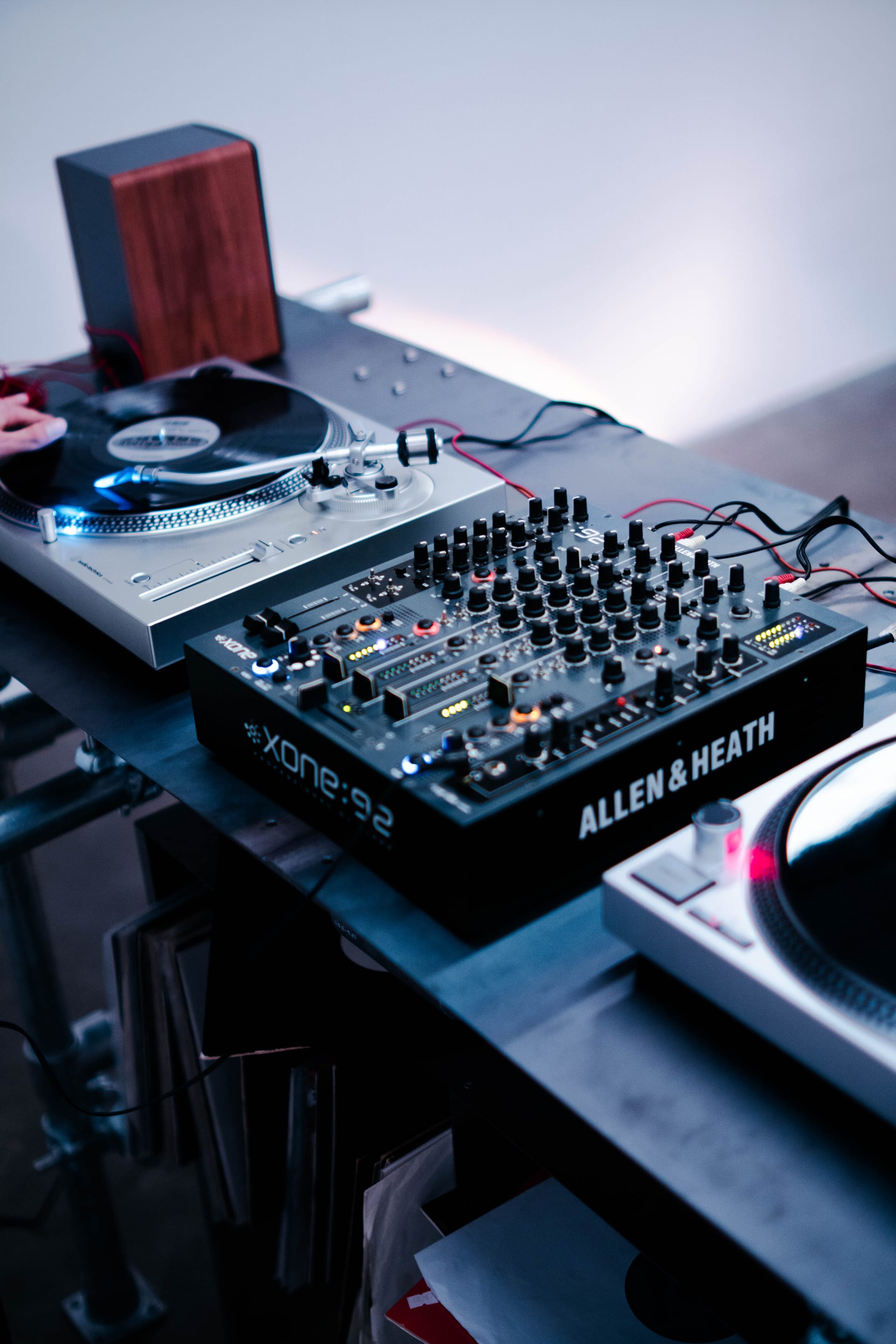 A close-up view shows the DJ set placed on the metal plate tabletop of the DJ table.